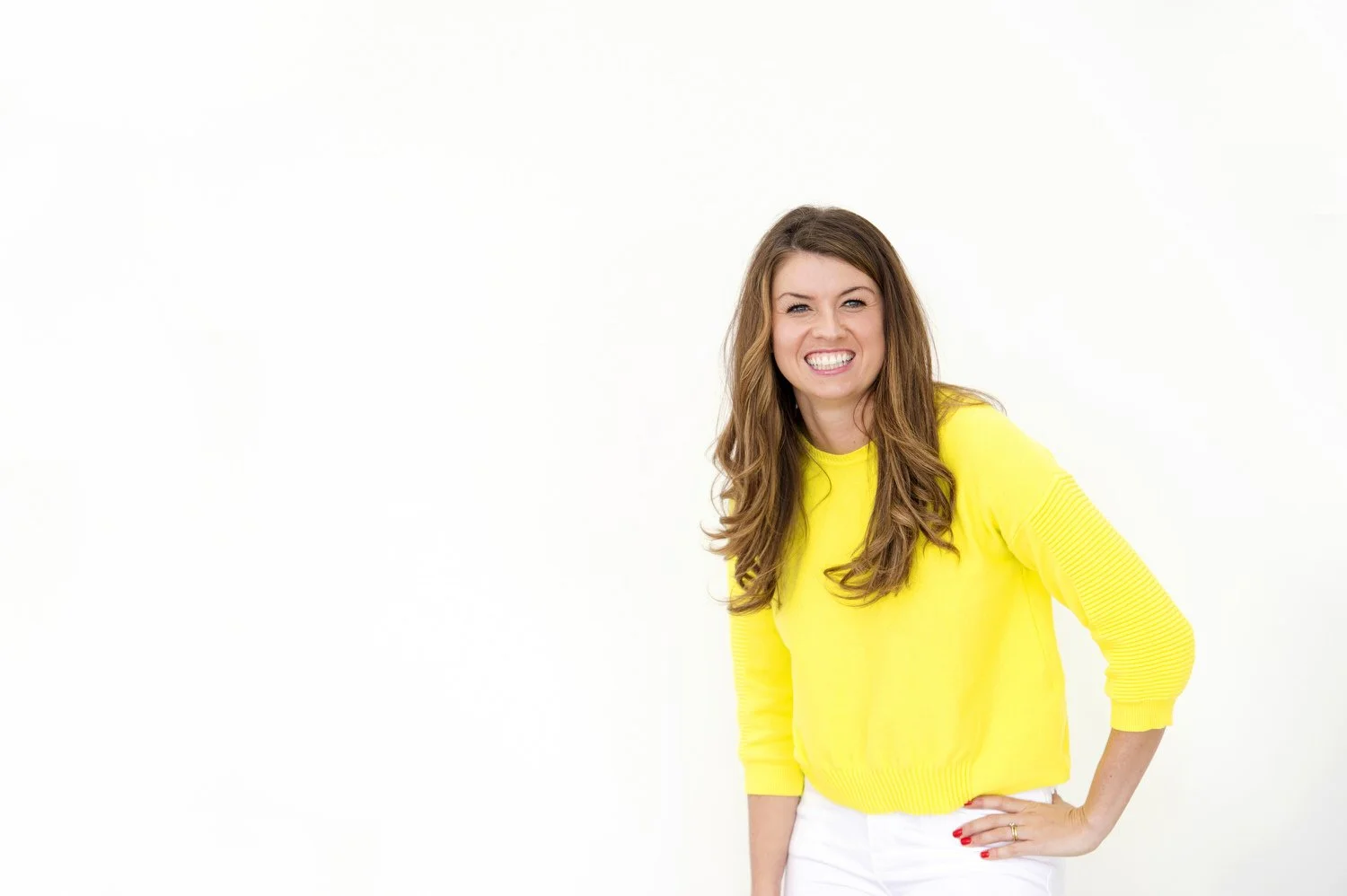 Business Woman Rachael Flanagan of Mrs Bucket cleaning, pictured smiling and wearing a yellow sweater and white pants, standing against a white background.