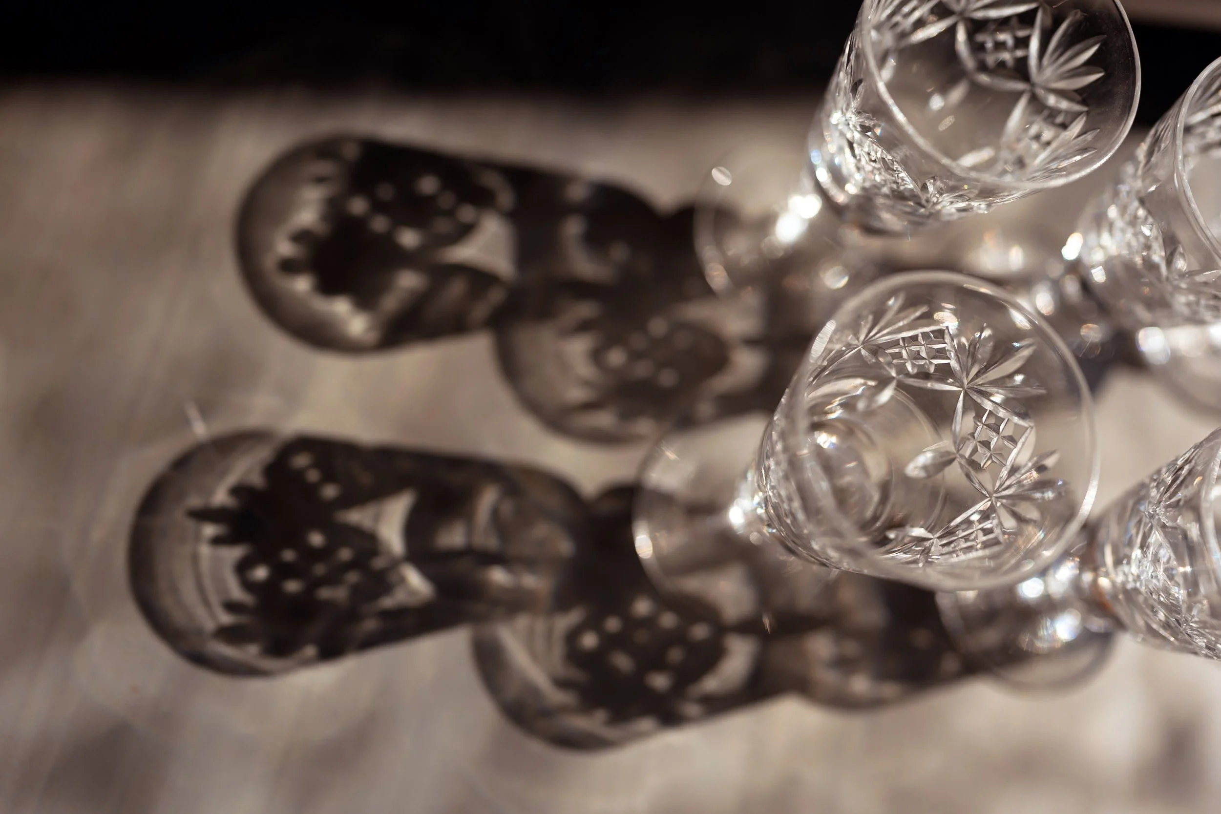 Three crystal glasses casting intricate, patterned shadows on a light surface—perfect for elegant product photography.