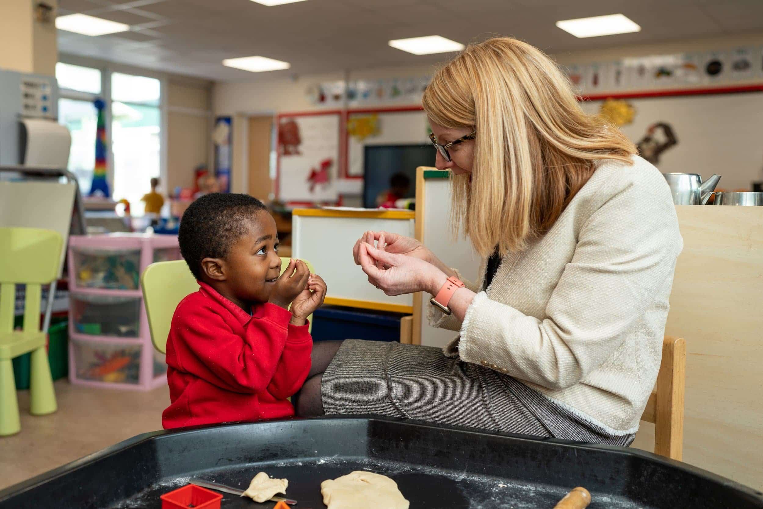 Young school child and a head teacher interacting in a school room setting.