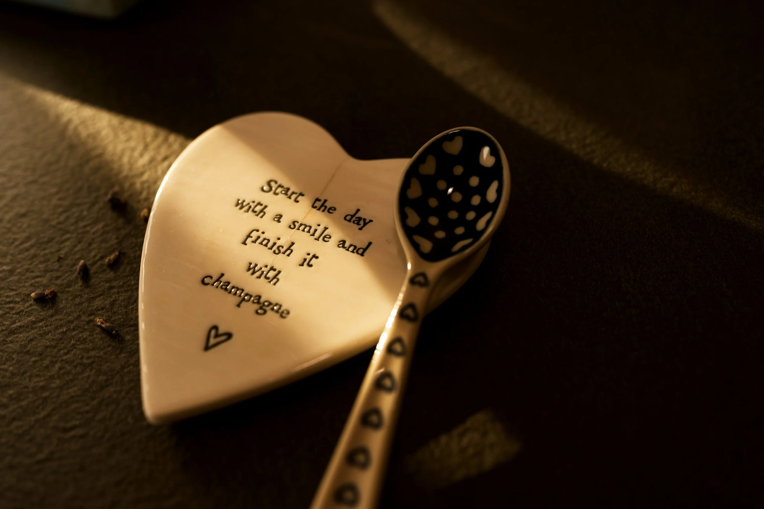 Heart-shaped ceramic plate product with inspiring quote, styled for product photography alongside a decorative spoon.
