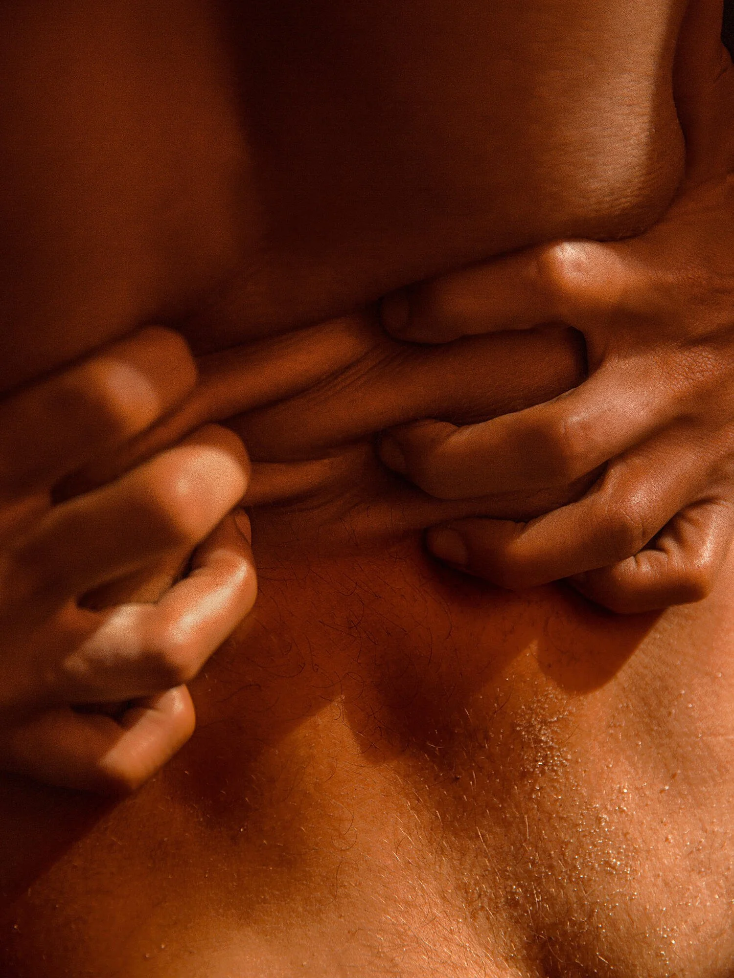 Close-up of a person's hand squeezing the skin of another person's body, revealing the texture and hair.