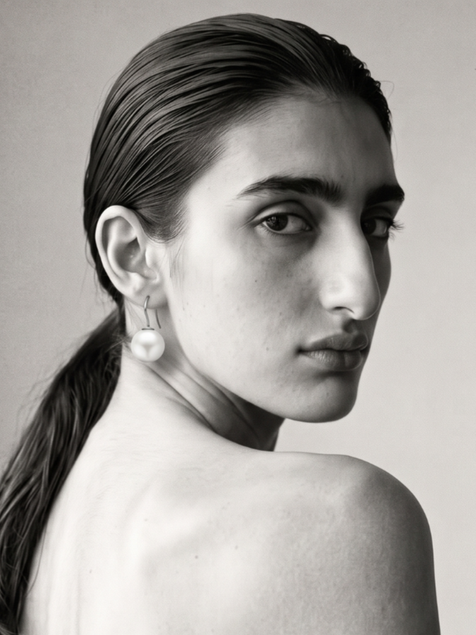 Black and white portrait of a woman with wet hair, wearing a pearl earring, looking over her shoulder.