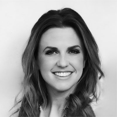 Black and white portrait of a woman with long wavy hair smiling.