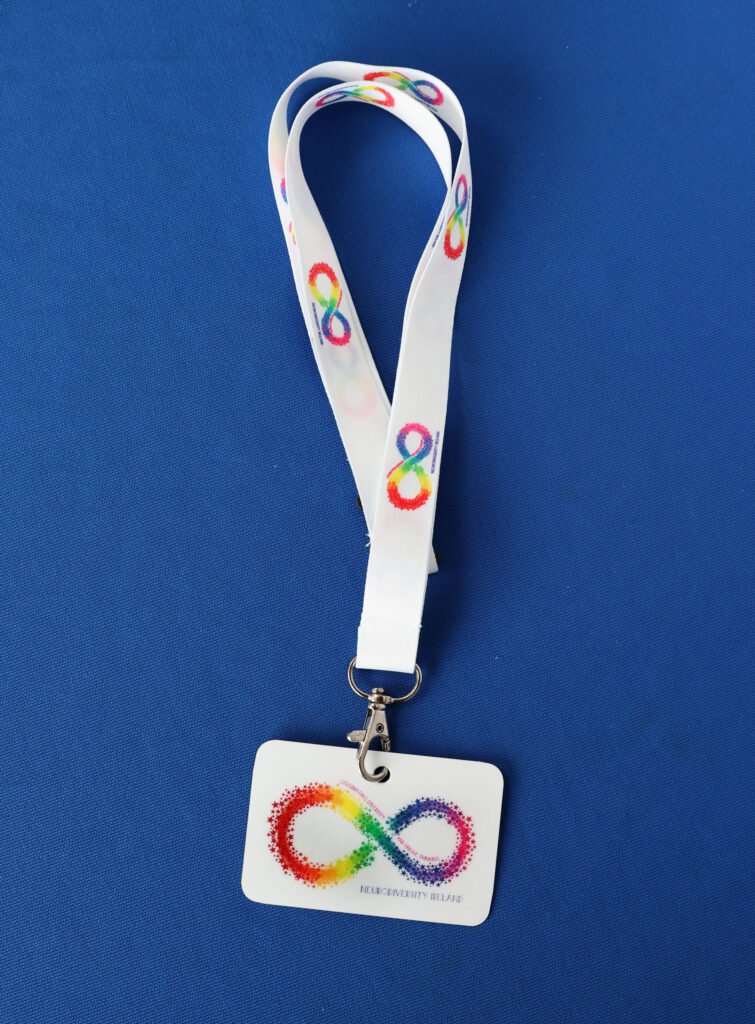 Lanyard with a badge featuring a rainbow infinity logo and the text 'NEURODIVERSITY ISLAND' on a blue background.