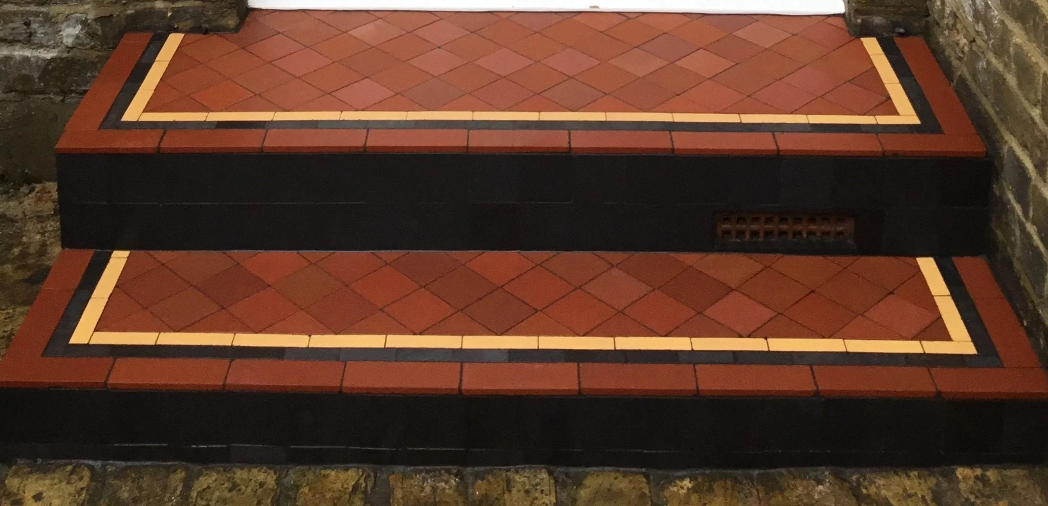 Steps in a Dulwich workers cottage, tiled with victorian red 3 inch tiles with a yellow strip border and black risers
