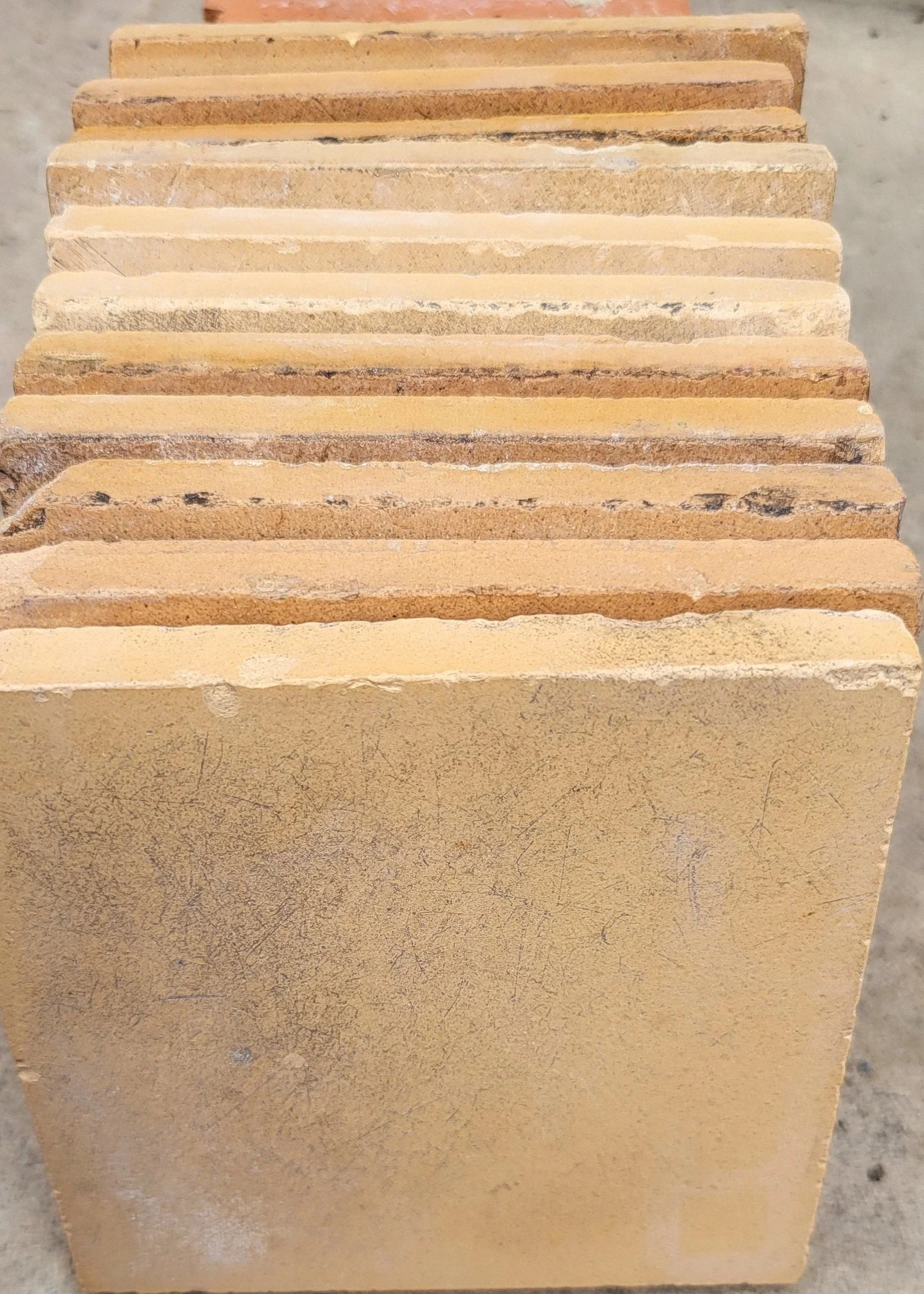 Close-up photo of a stack of 4 inch yellow vintage tiles.