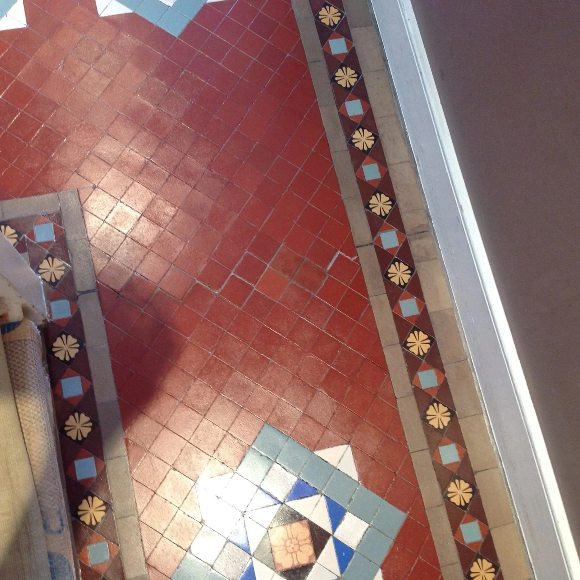 Close-up of a decorative tiled floor with red, beige, blue, and cream patterns and border design.