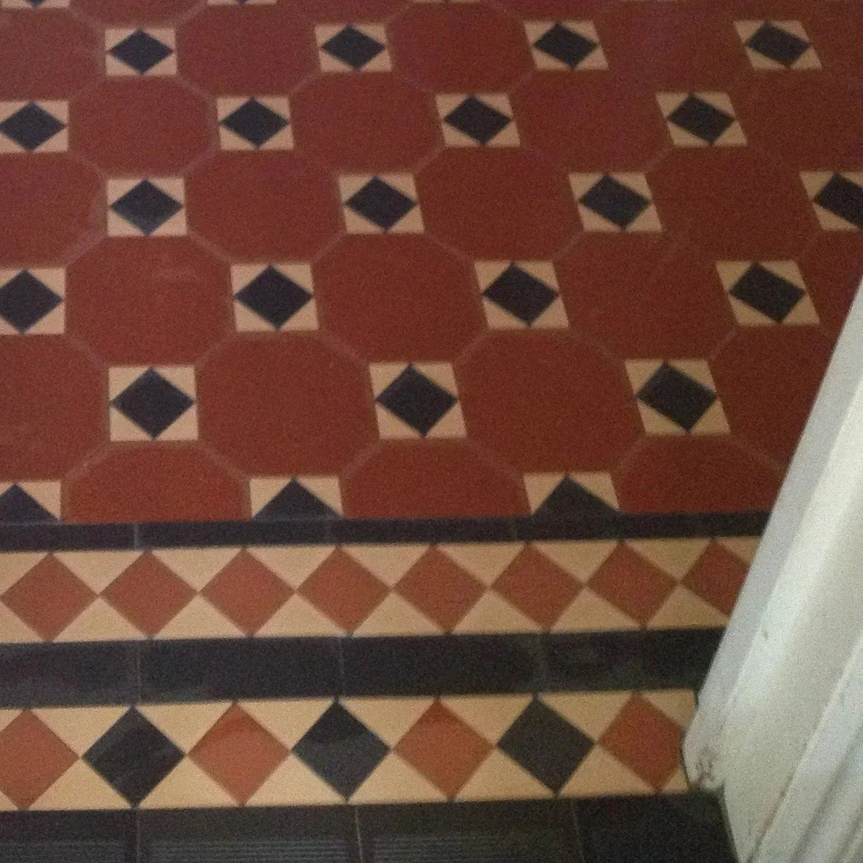 Patterned floor tiles with geometric shapes in red, black, and beige colors, featuring octagons, squares, and diamond shapes.