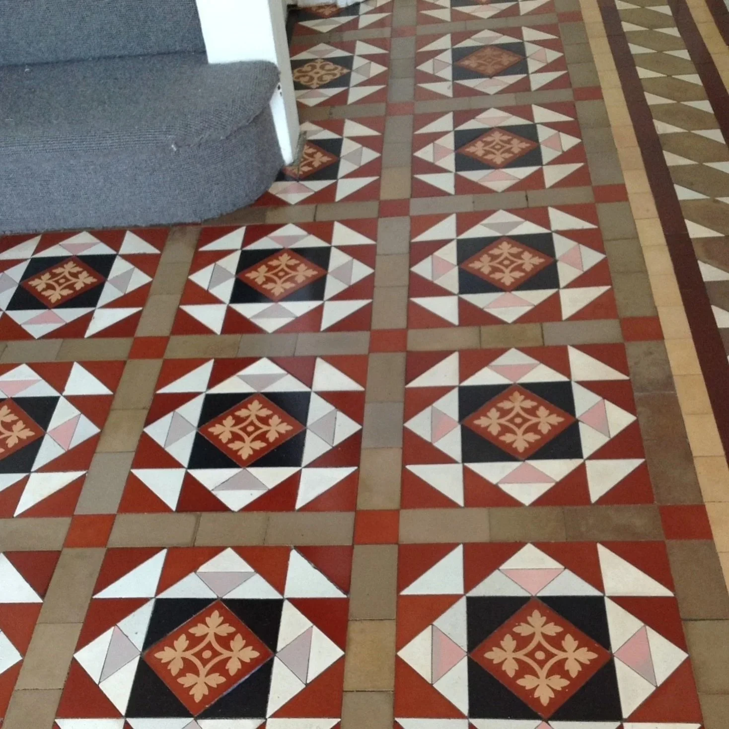 A patterned tiled floor with red, black, white, coffee and pink tiles