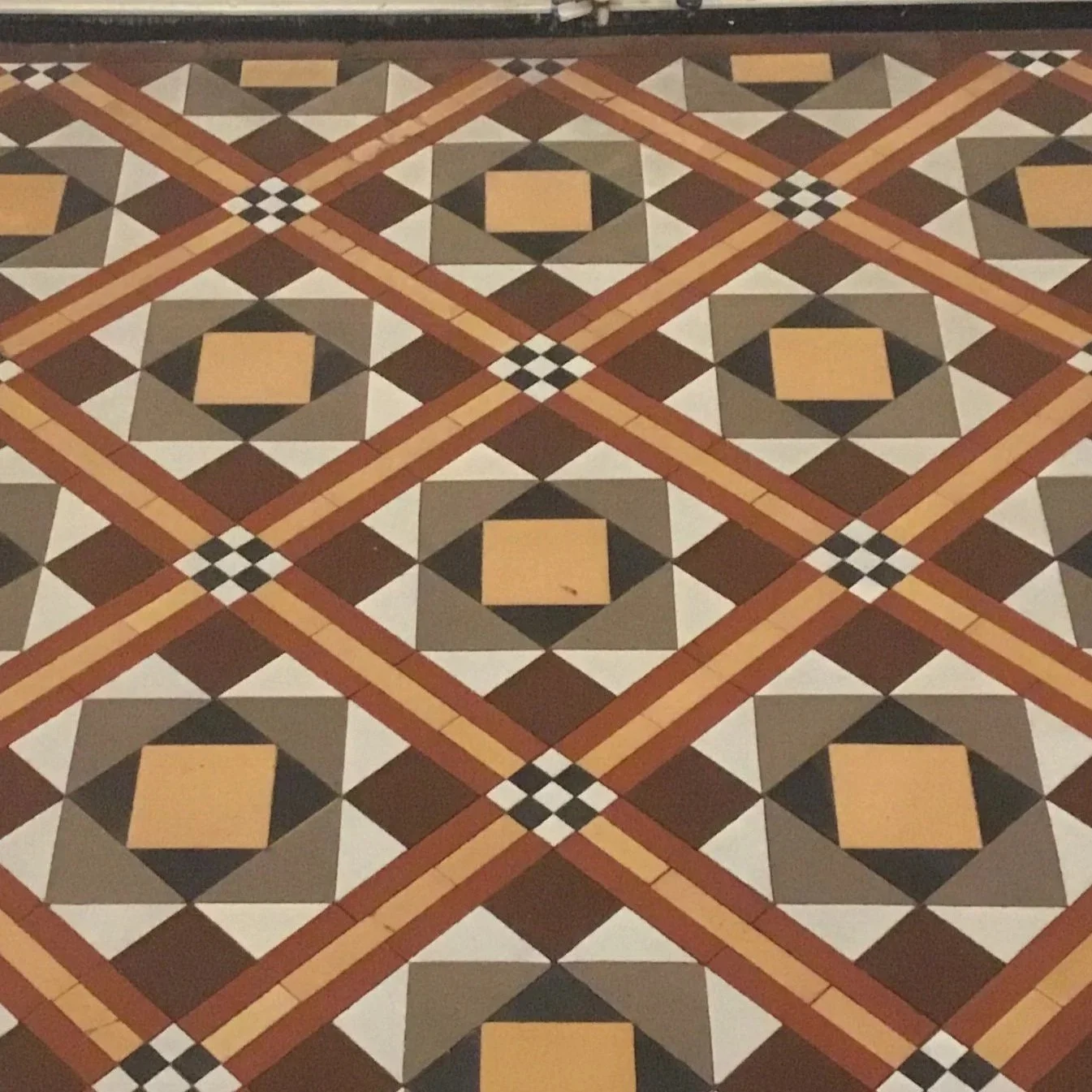 Patterned vintage mosaic hallway with repeated motifs and tile sizes varying from 4 to 1 inch squares