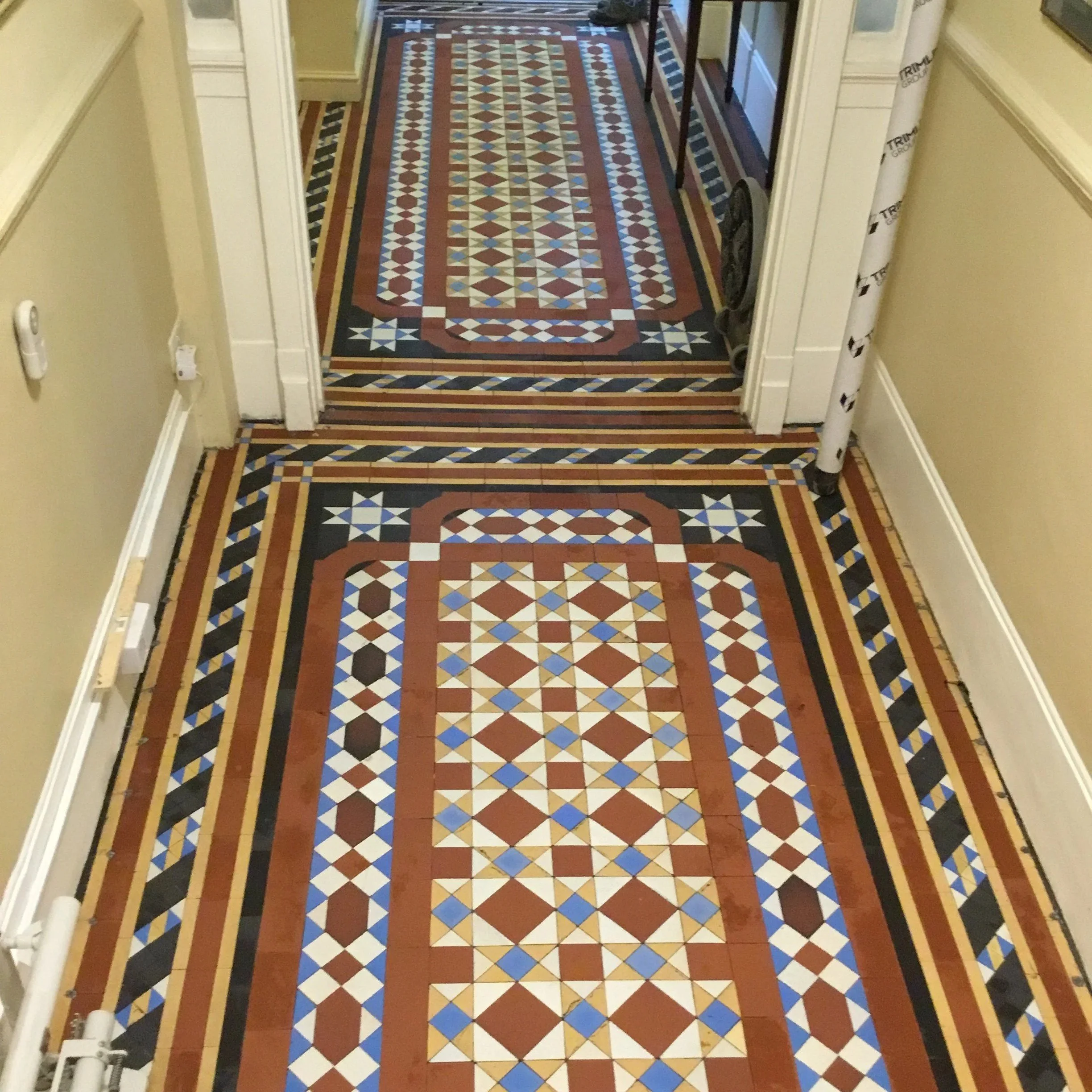 Decorative geometric tile floor with various colors and patterns leading into a room.