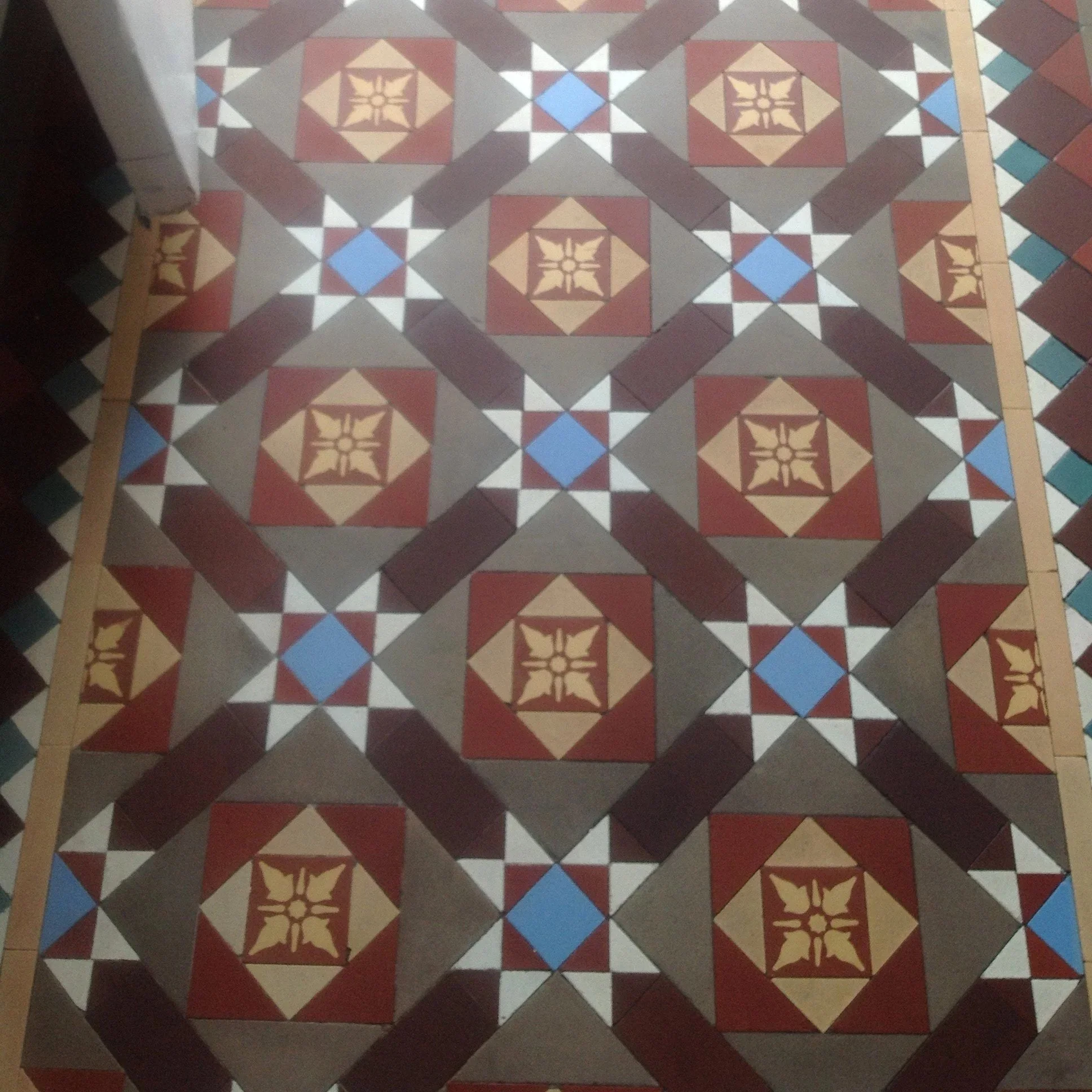 Decorative tiled floor with geometric patterns in red, beige, white, gray, and blue colors.