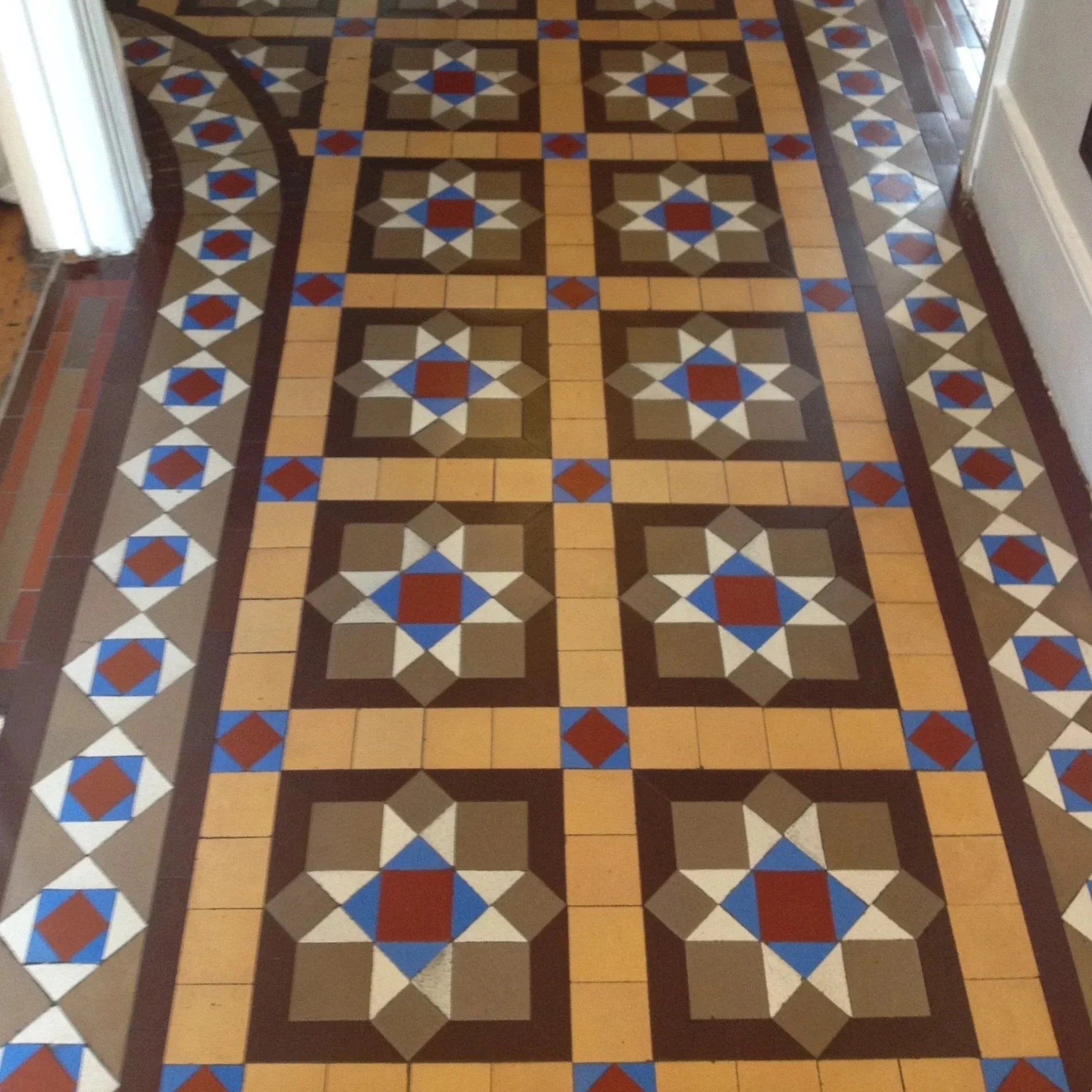 Decorative tiled floor with geometric patterns in brown, beige, blue, red, and white, featuring star and square designs.