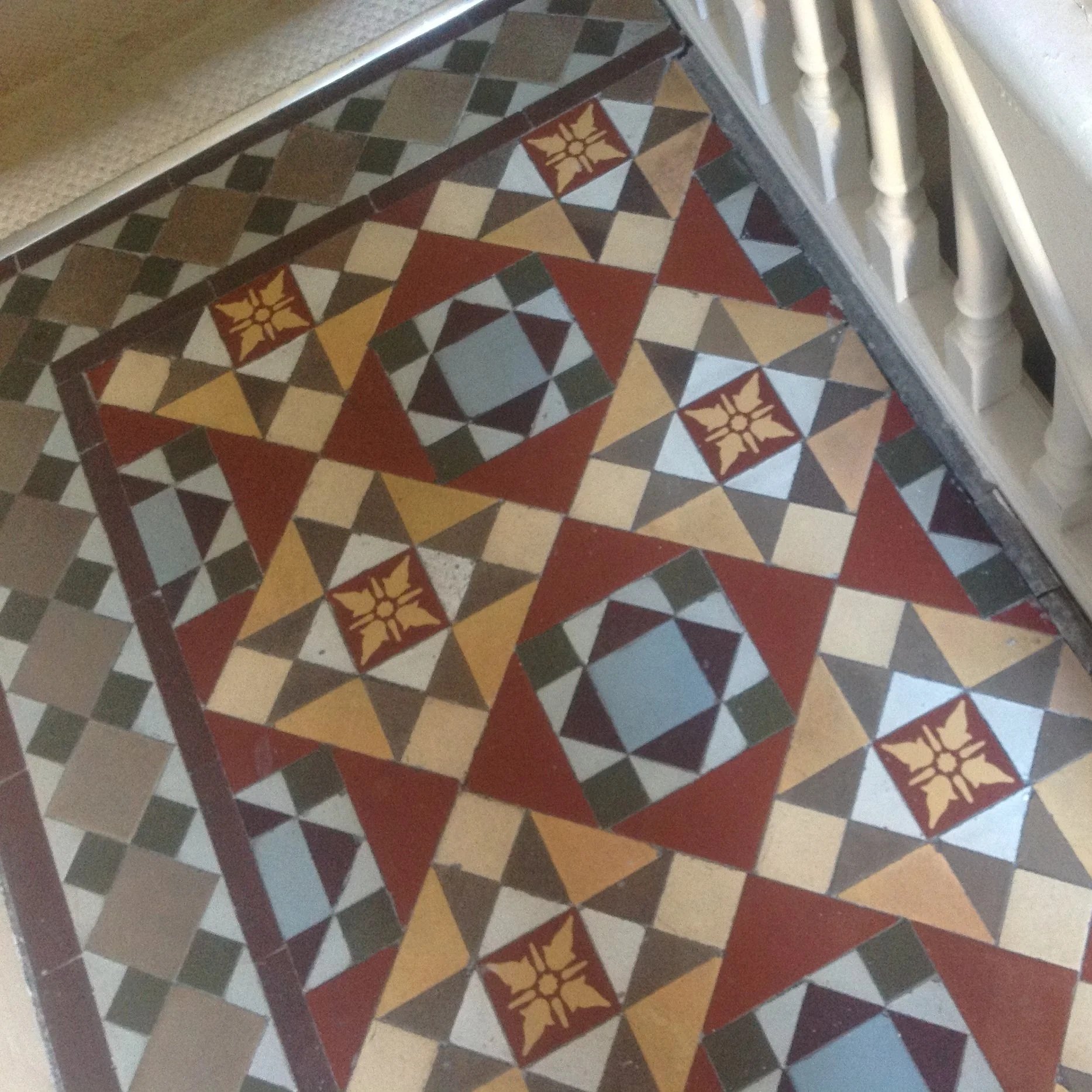Decorative tiled floor with geometric patterns in red, yellow, black, gray, and blue, including floral motifs.