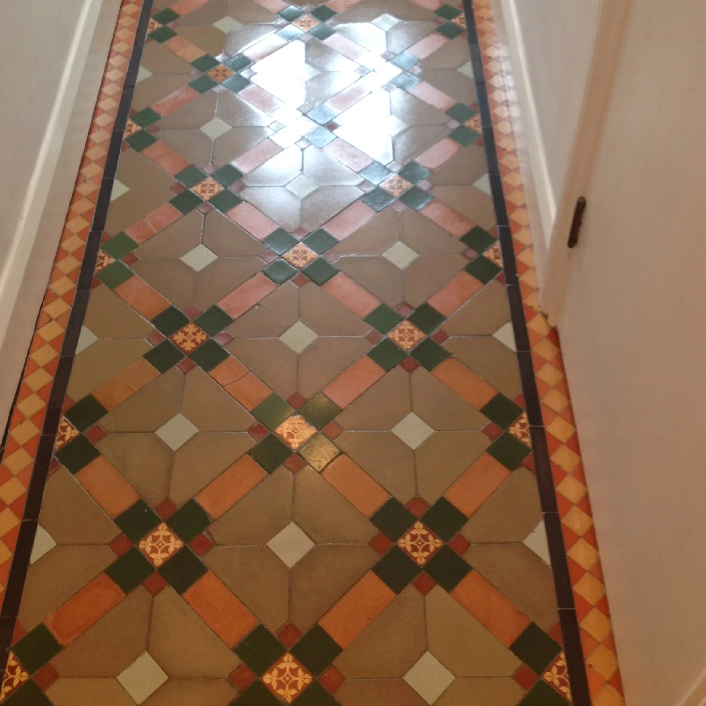 Patterned tile floor in beige, green, orange, and cream colors, with decorative borders.