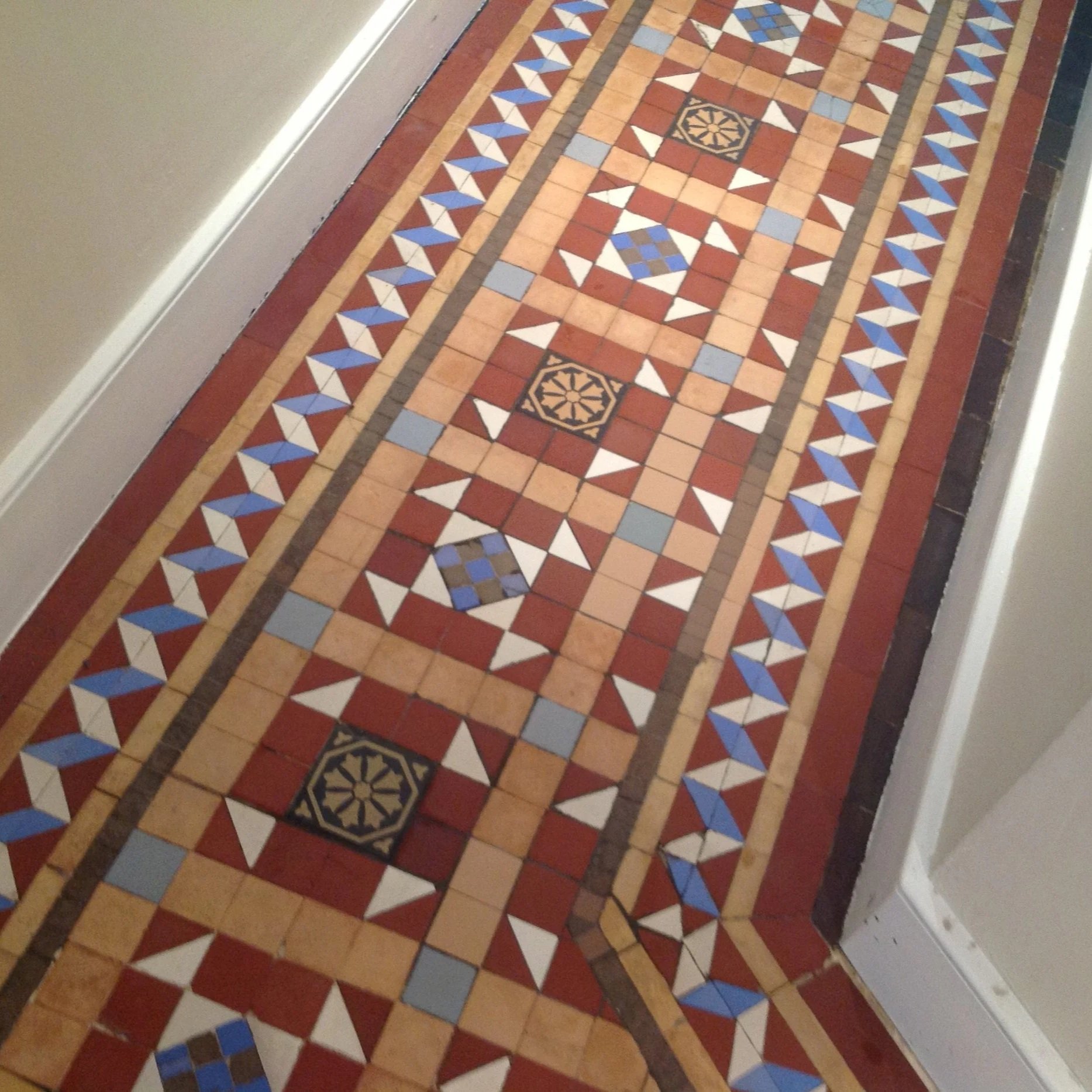 Colorful mosaic tile floor in a hallway with geometric patterns and decorative details.