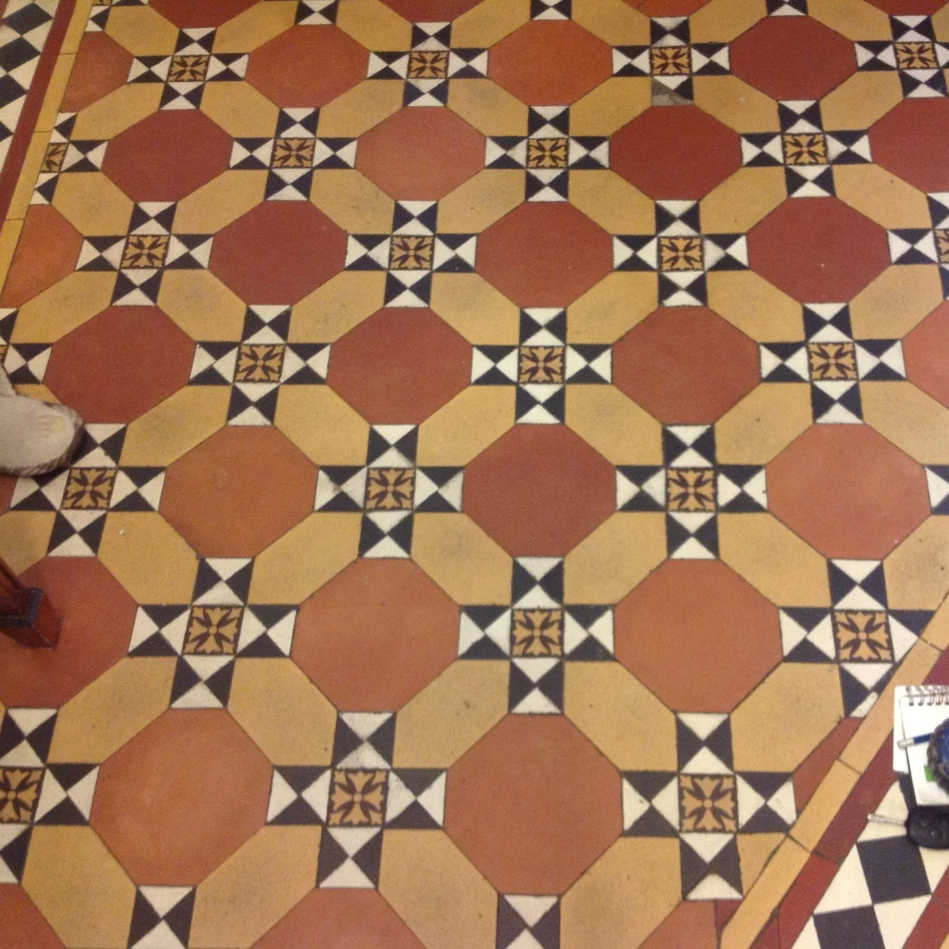 Patterned tile floor with red, yellow, black, and white geometric designs.