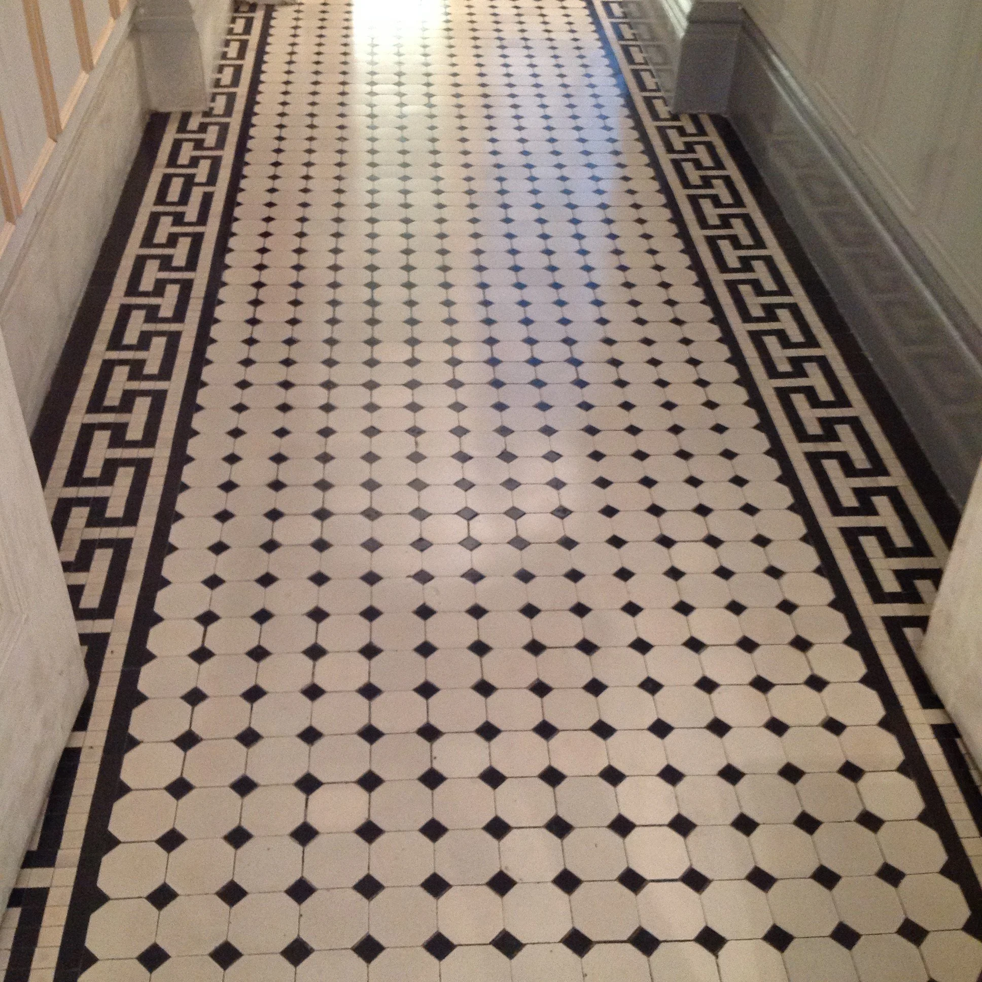 A patterned communal ground floor hallway in central London with a white octagon and dot design and featuring a border with a Greek key design.