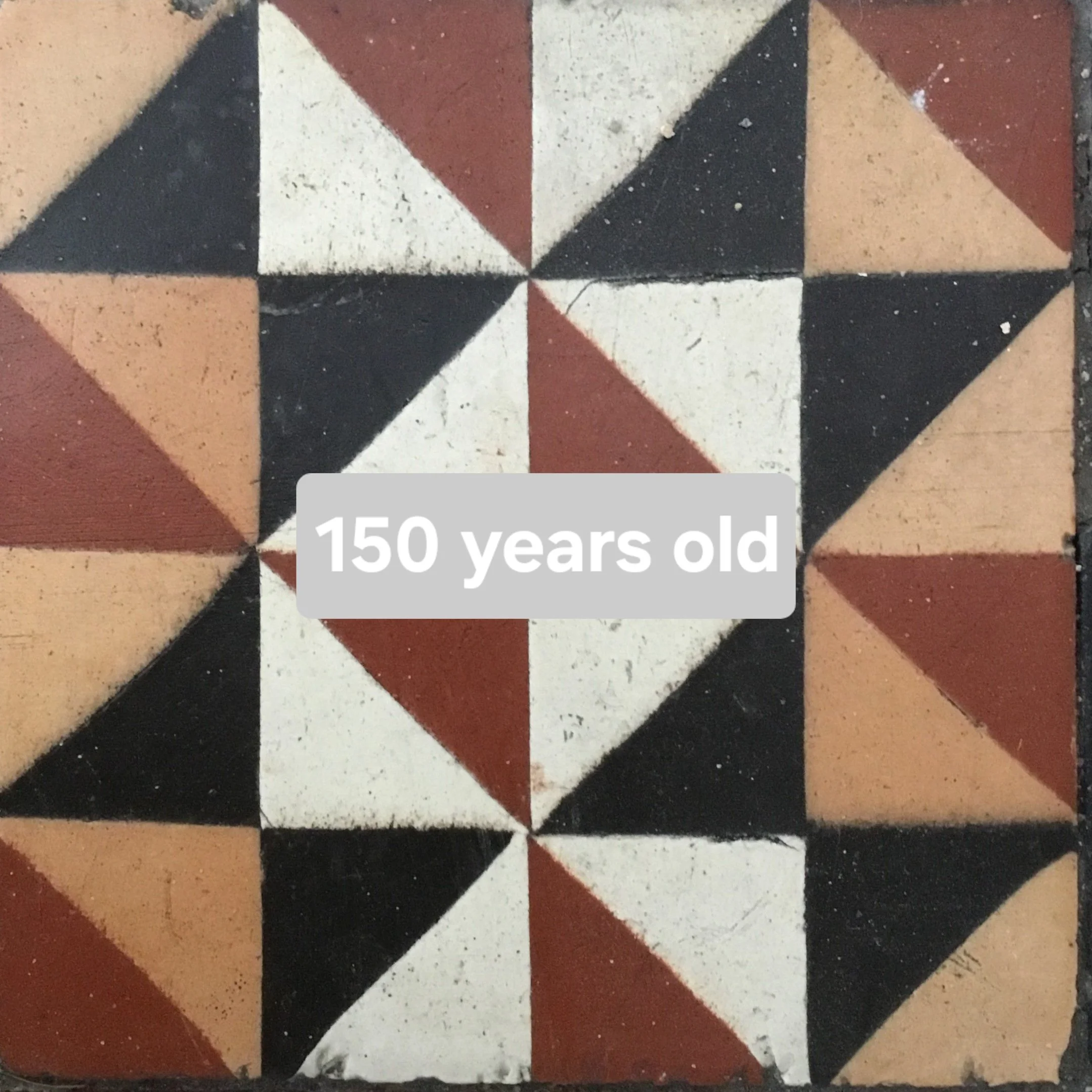 Decorative vintage tile pattern in black, white, red, and beige colors with a label stating "150 years old."