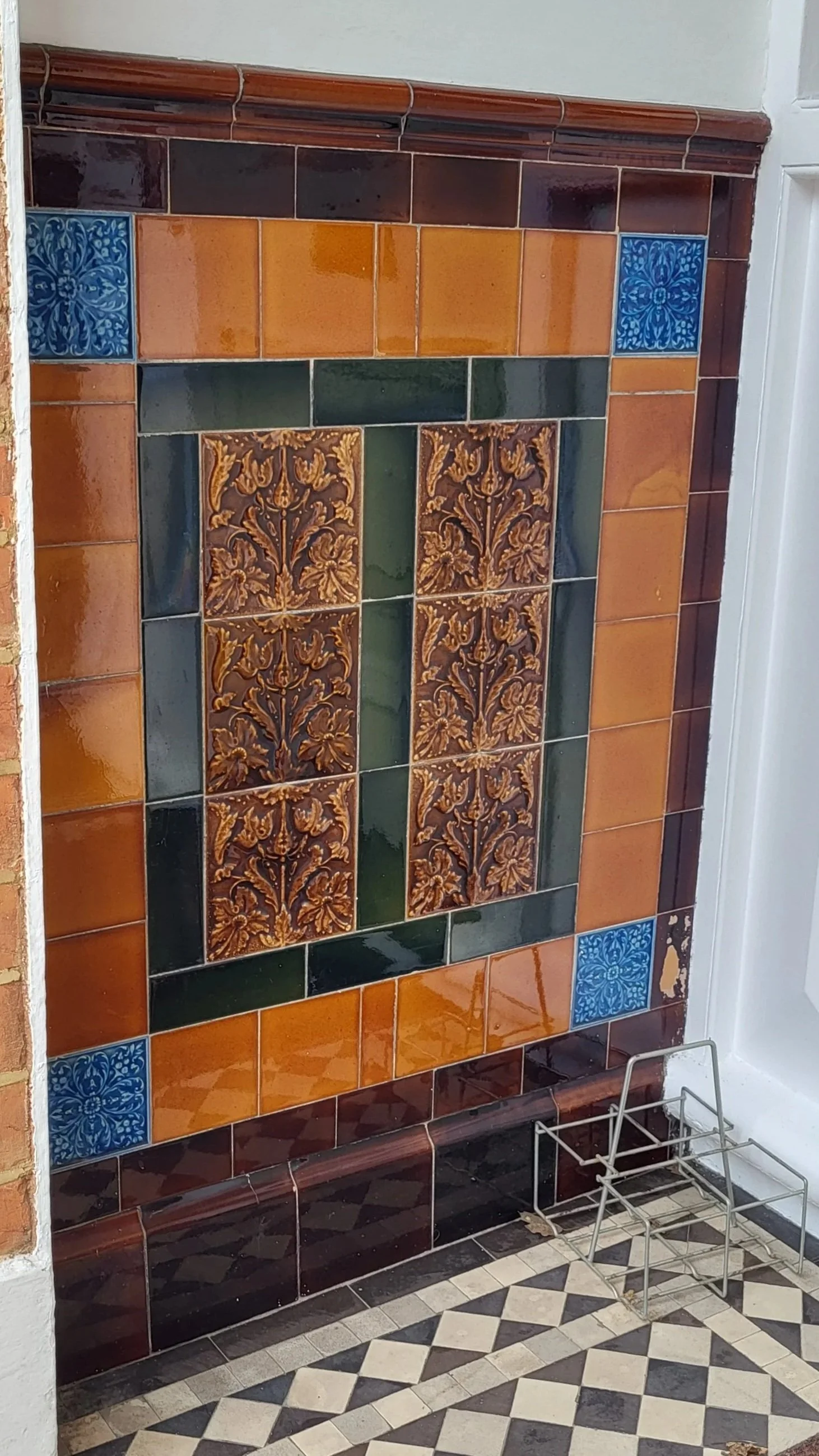 Decorative tiled wall with orange, green, blue, and brown tiles with a black and white checked tiled porch