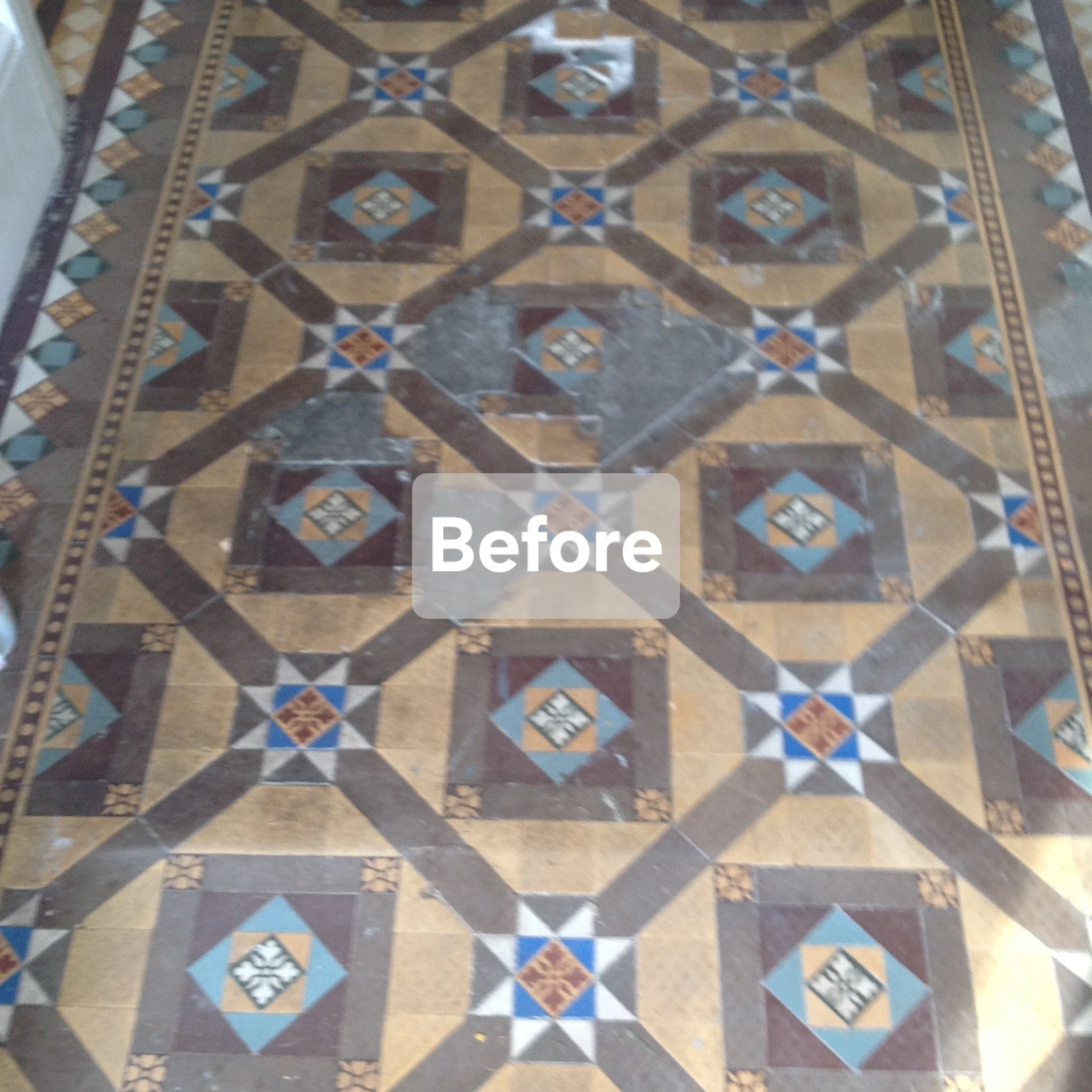 Before photo of a patterned tile floor with a central 3x3 grid of decorative tiles, some of which are scratched and damaged.