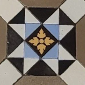 Close-up of a tiled floor pattern with black, white, blue, and beige tiles arranged in a geometric design.