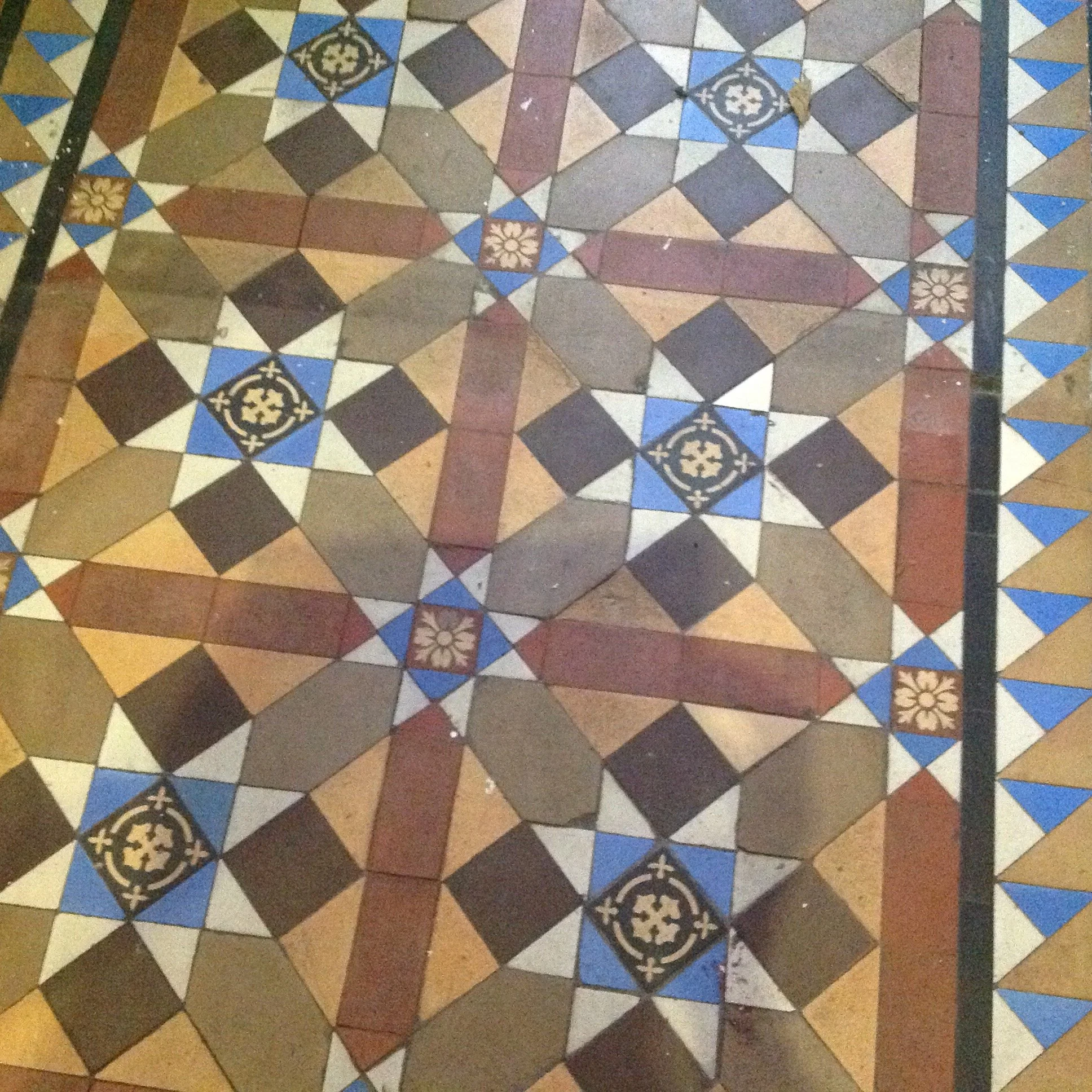 Colorful decorative tiled floor with geometric patterns and intricate designs in shades of brown, black, white, red, and blue.
