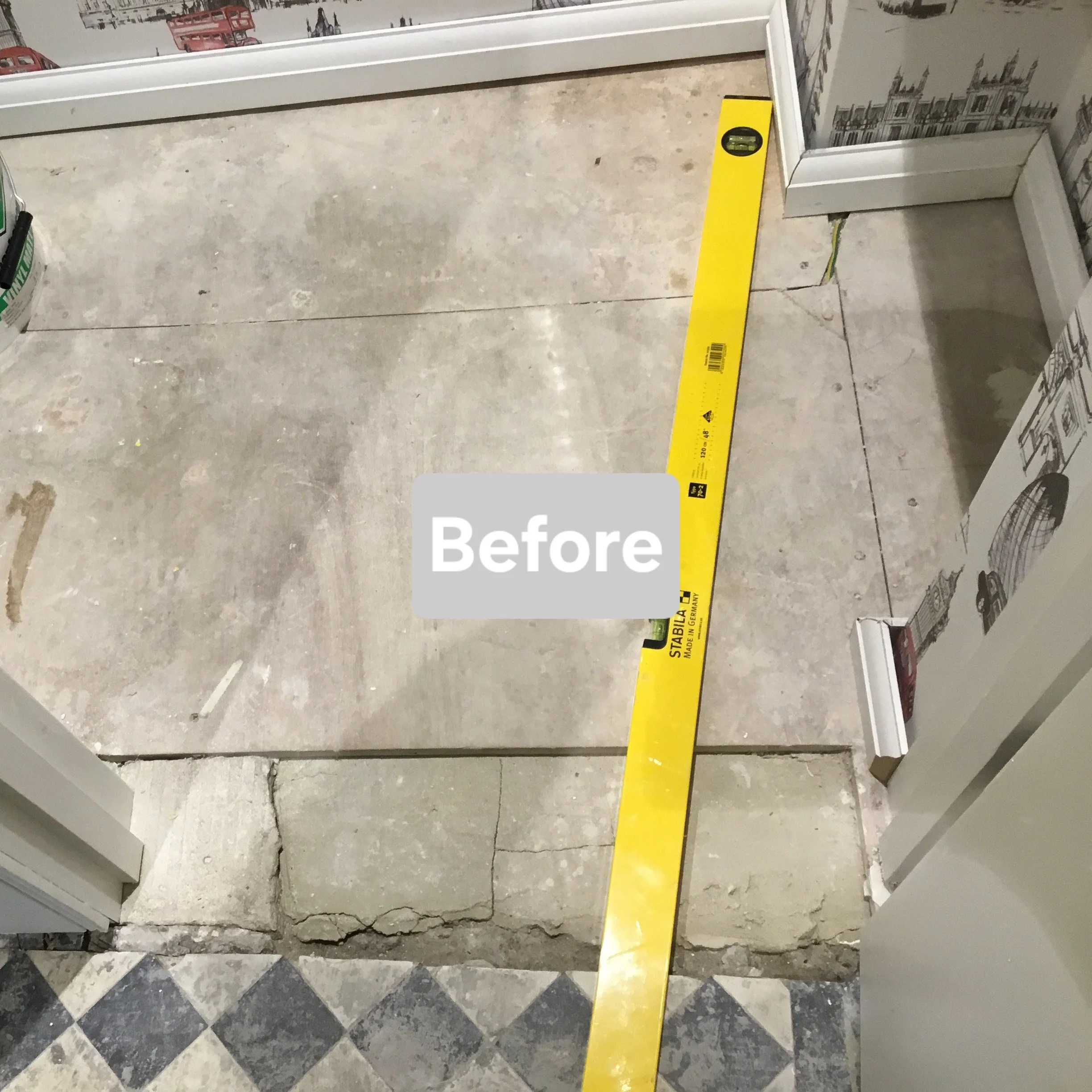 The image shows a construction or renovation area with an uneven floor. The lower part of the image includes a section of patterned tile flooring, while the upper part shows rough concrete with visible cracks and marks. A yellow level tool is placed 