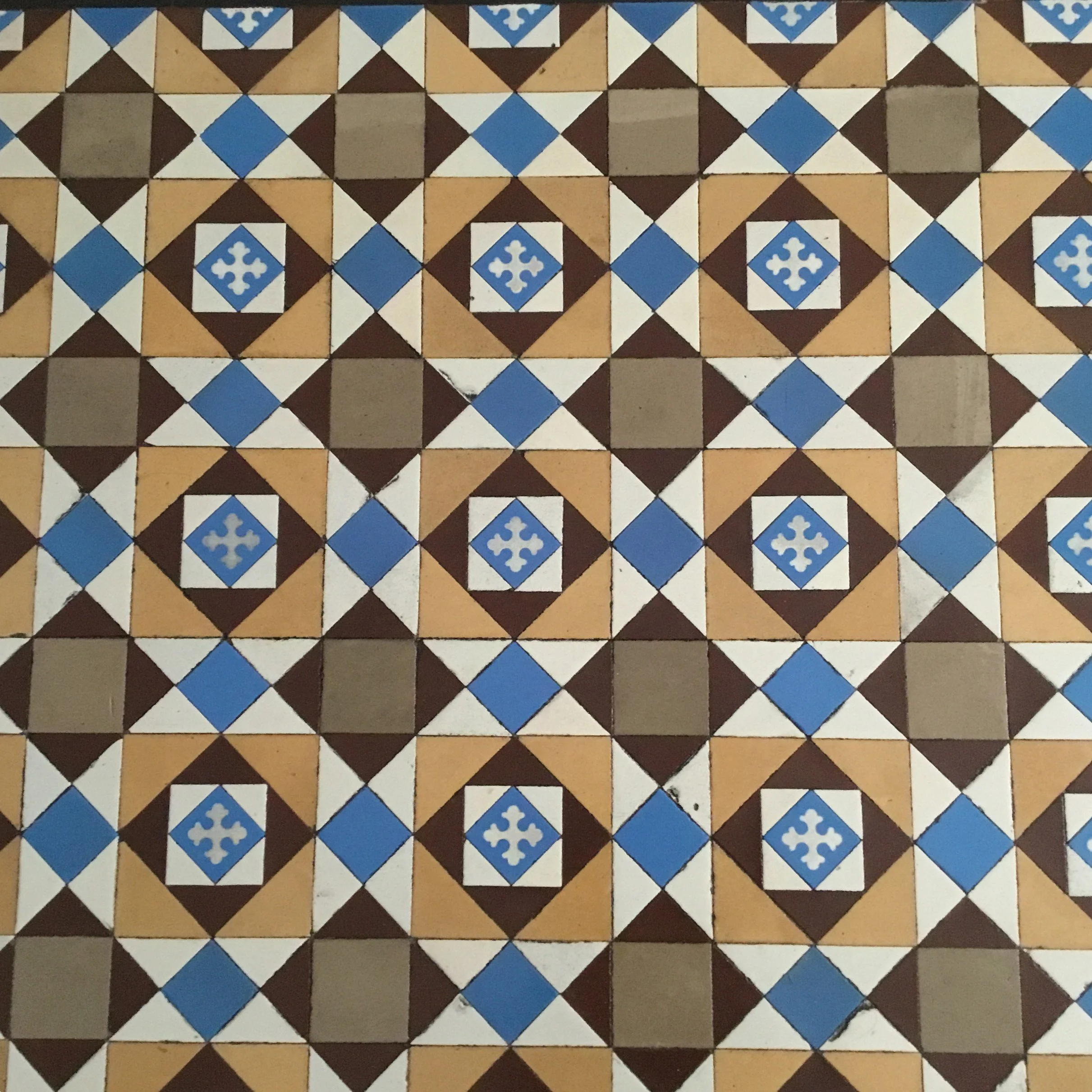 Patterned ceramic tiles with geometric designs in brown, white, blue, and tan colors.