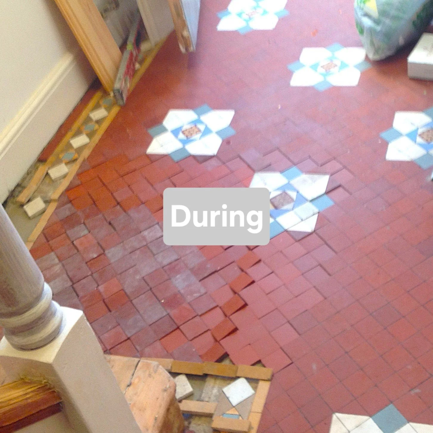 During home renovation, the brick floor is partially exposed with some tiles removed, revealing the subfloor beneath. The remaining tiles are red, and some decorative patterned tiles are visible on the floor.