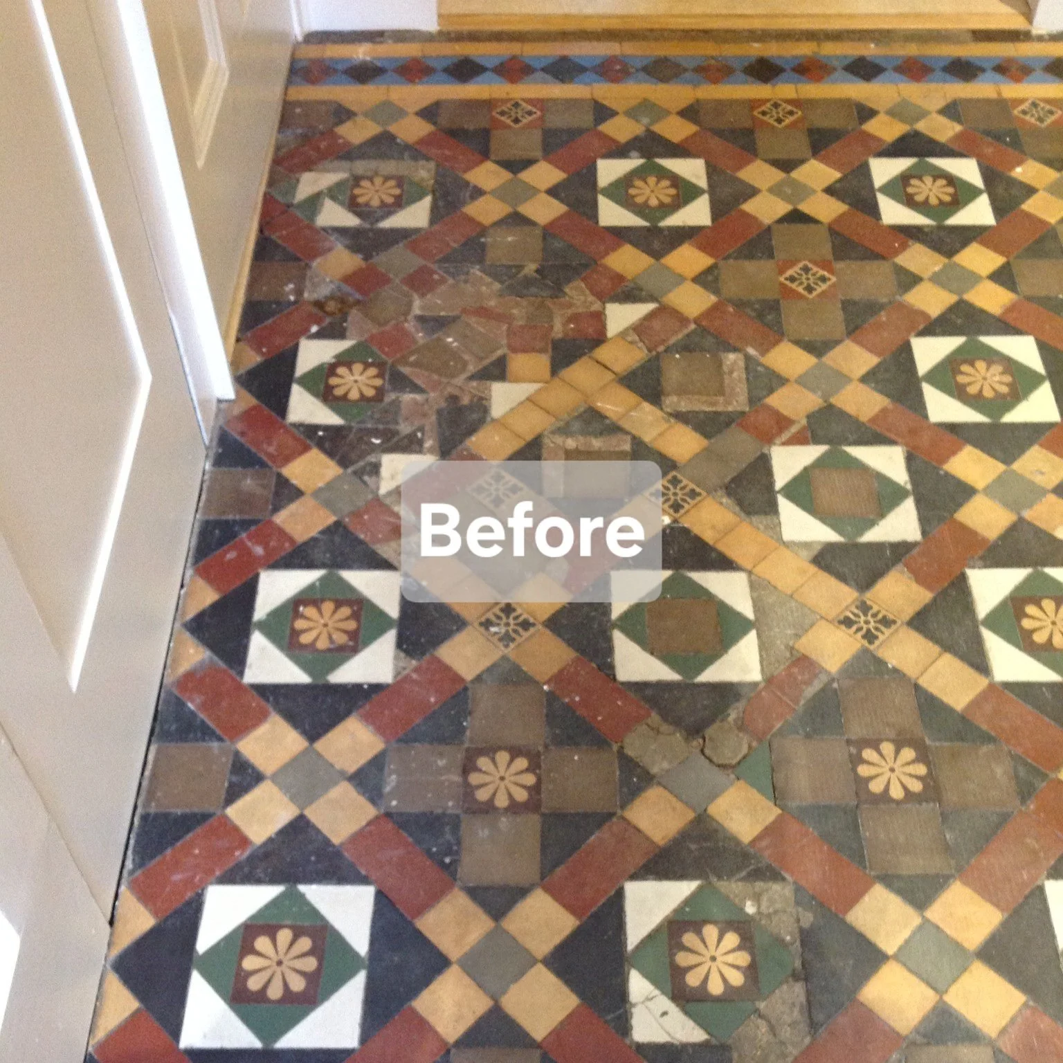 Vintage patterned tile floor with geometric designs and floral motifs, partially worn and damaged near the wall.