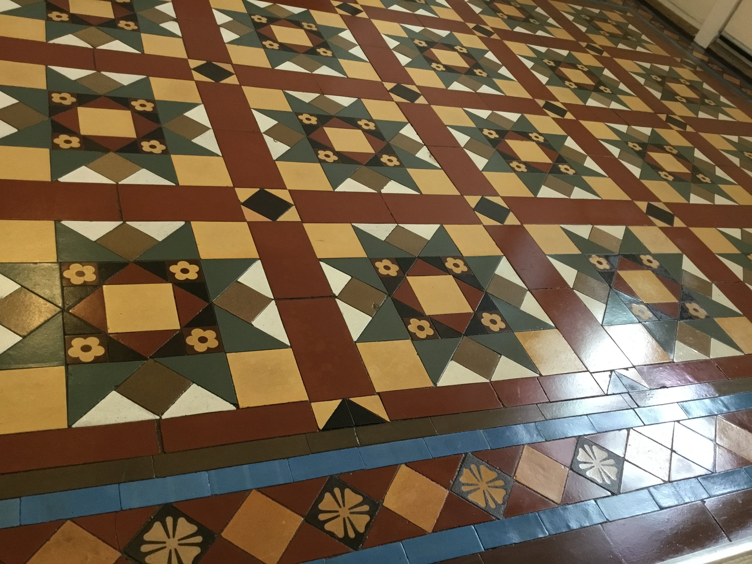 Colorful tile floor with geometric and floral patterns in shades of yellow, green, red, and black.