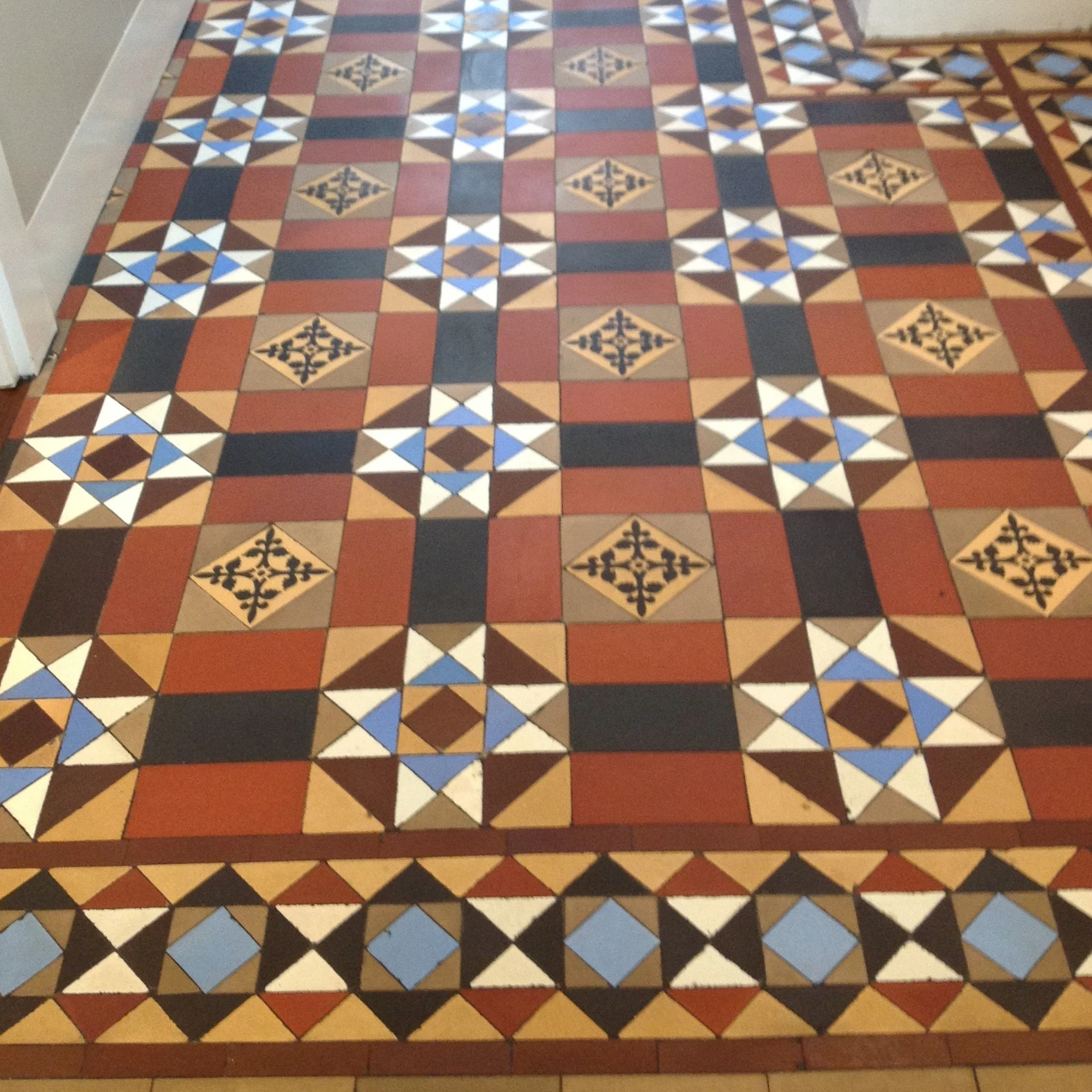 Patterned tile floor with geometric motifs in black, white, red, blue, and tan colors.