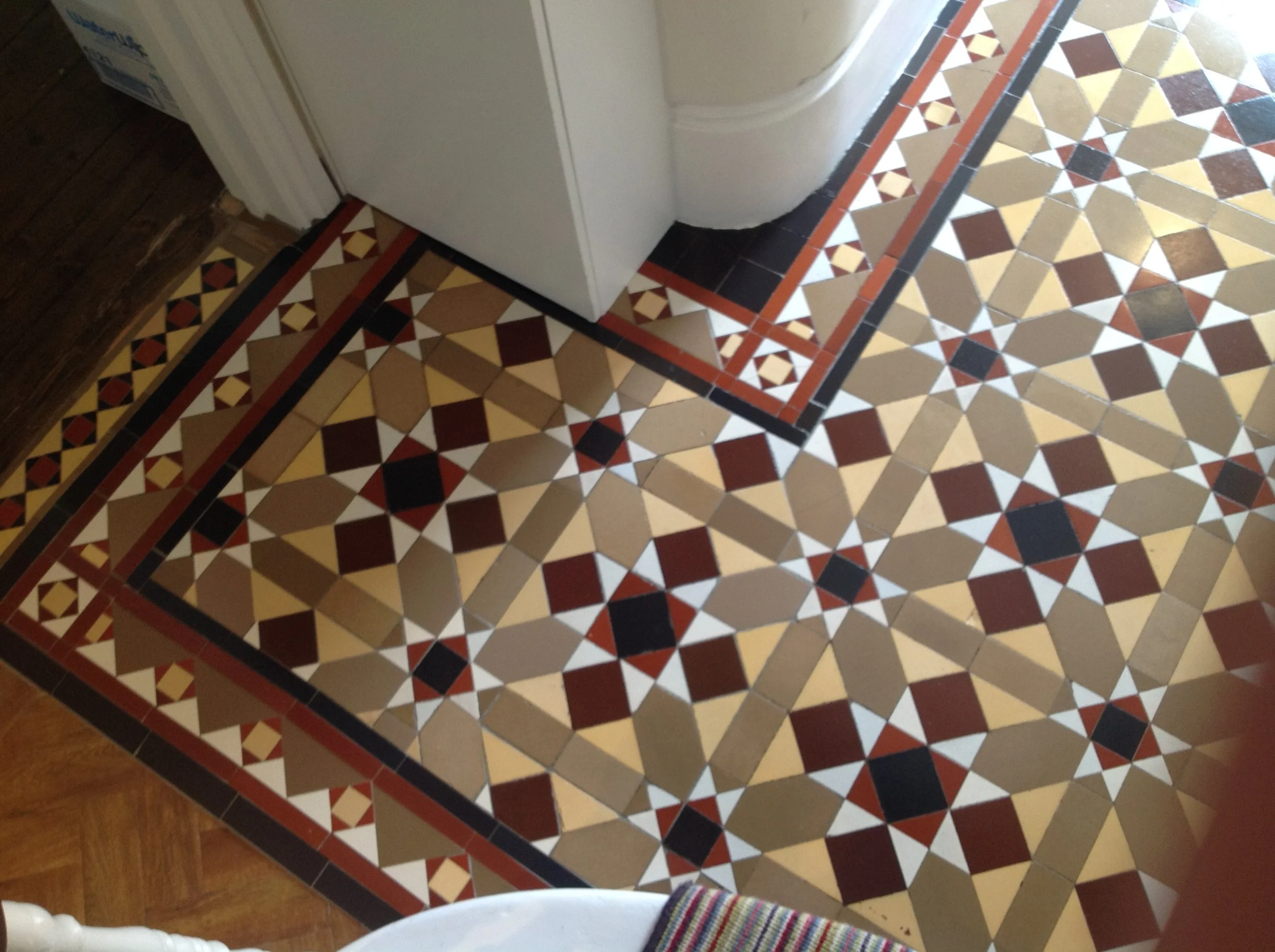 Decorative patterned tile floor area at the base of the stairs adjoining a wooden floor