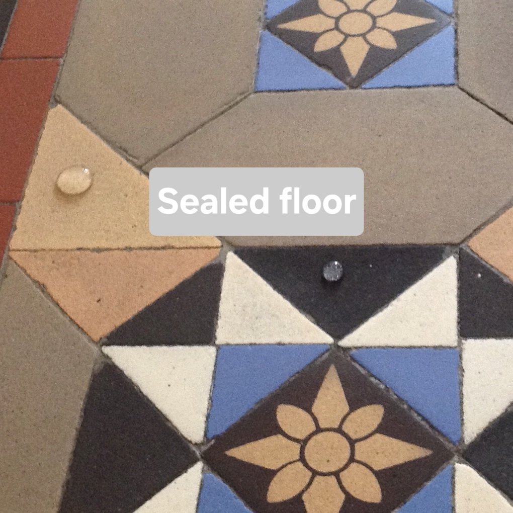 Close up of a clean floor with a drop of water on it forming a dome. The label says "Sealed floor."
