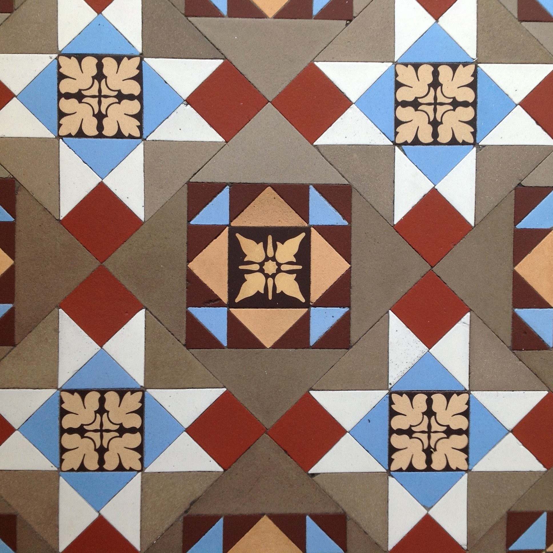 Patterned decorative tiles arranged in symmetric geometric design with colors including  coffee, white, blue, red, white, and .yellow