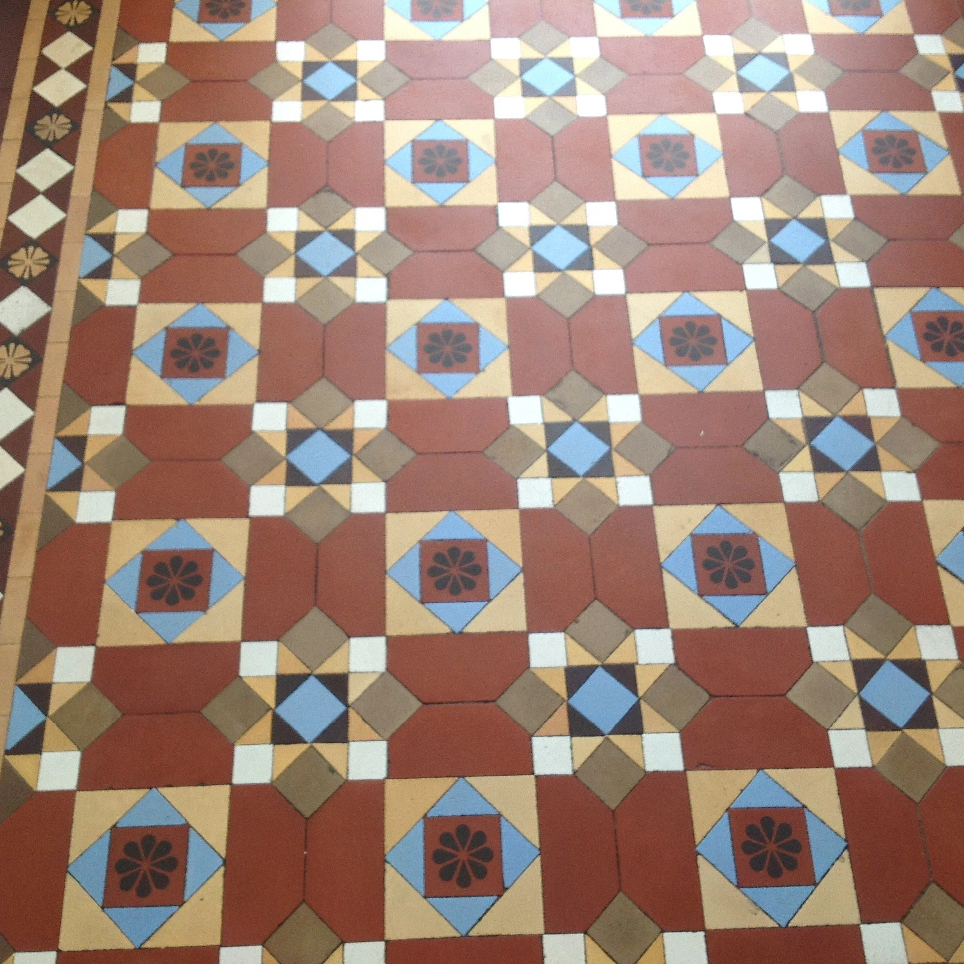 Patterned tile floor with half red octagons and blue and yellow tiles forming a  geometric design