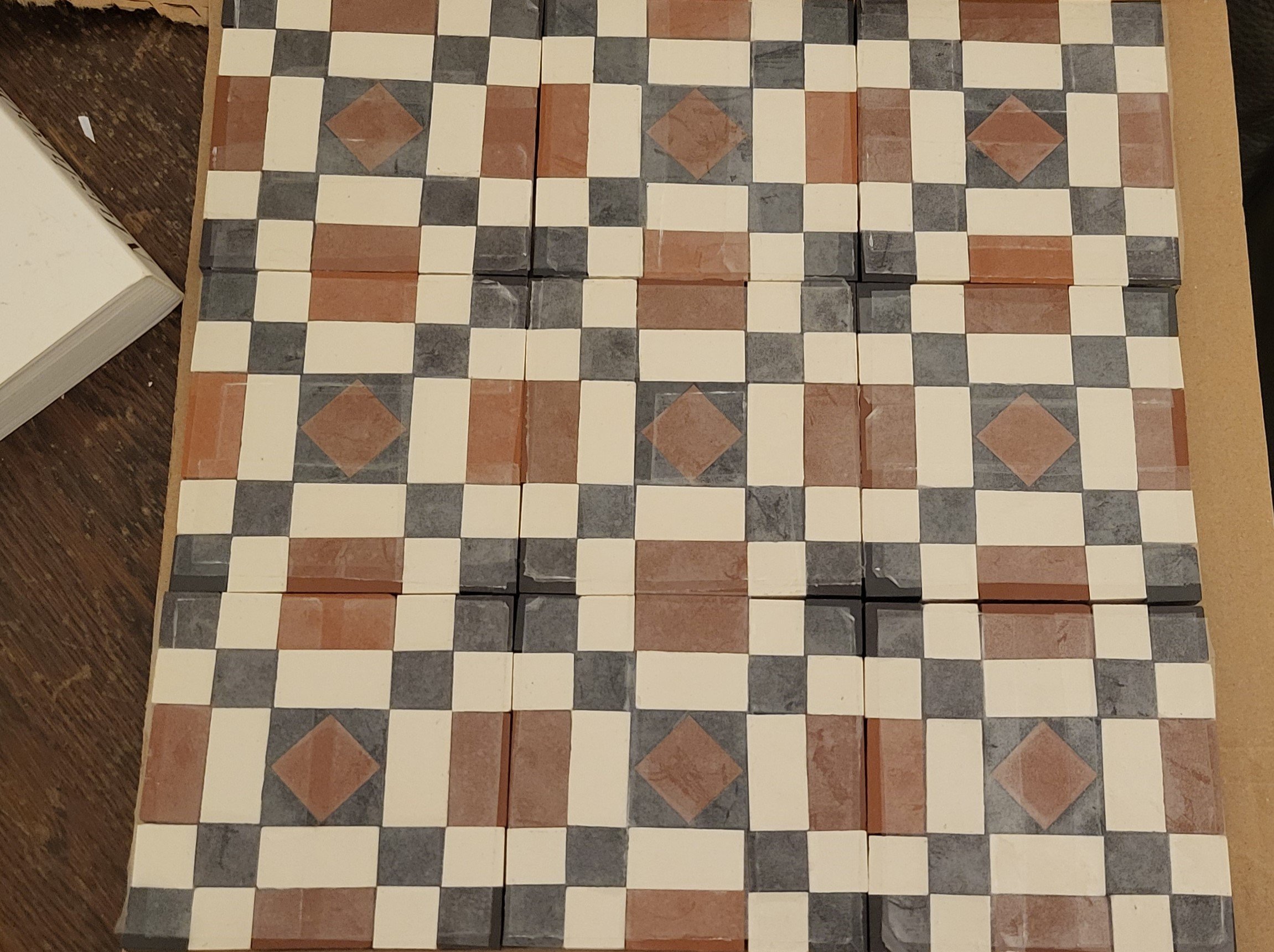 Collection of square patterned tiles arranged in a grid, featuring a geometric design with beige, black, and reddish-brown colors.
