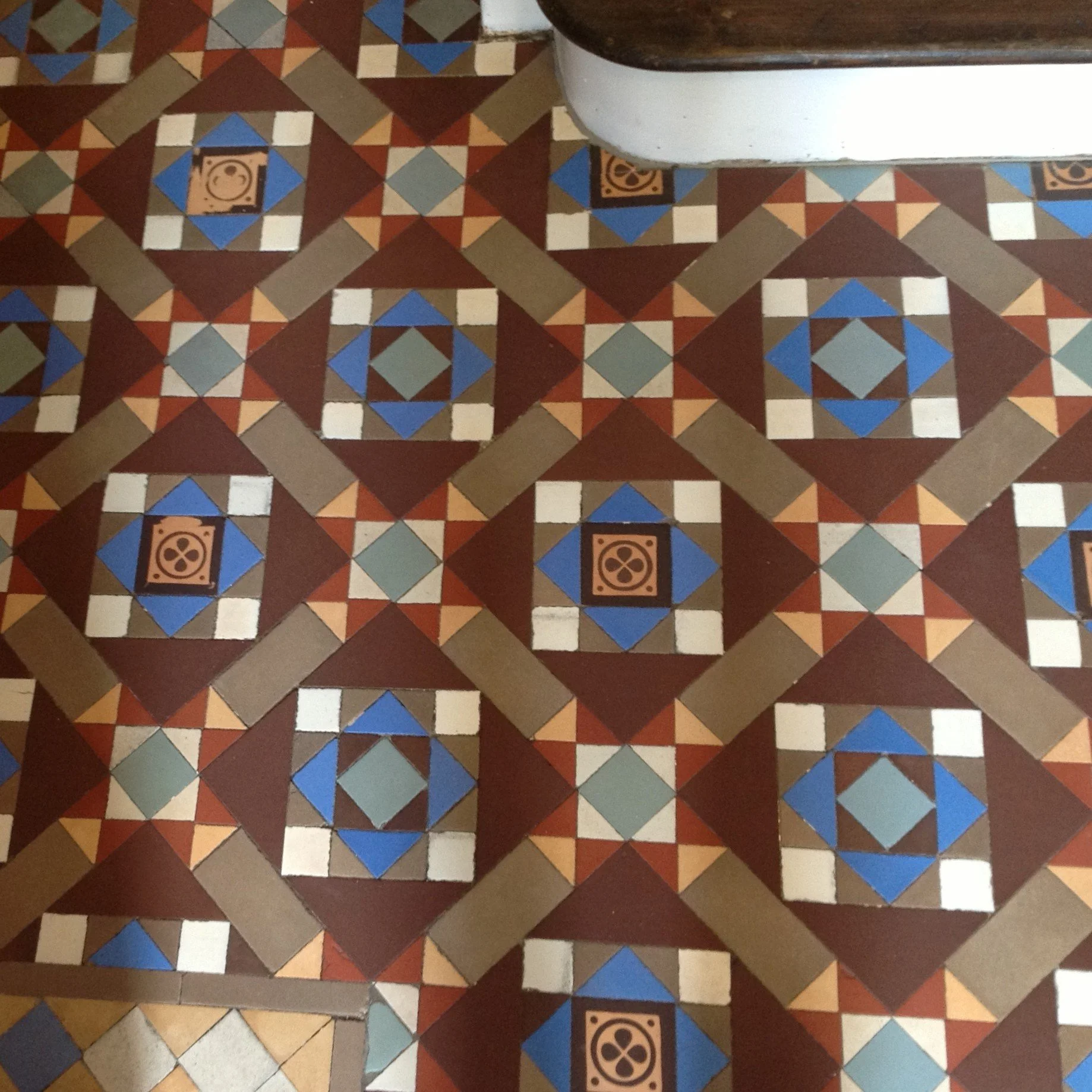Patterned ceramic tile floor with blue, white, brown, and beige geometric designs and floral motifs.