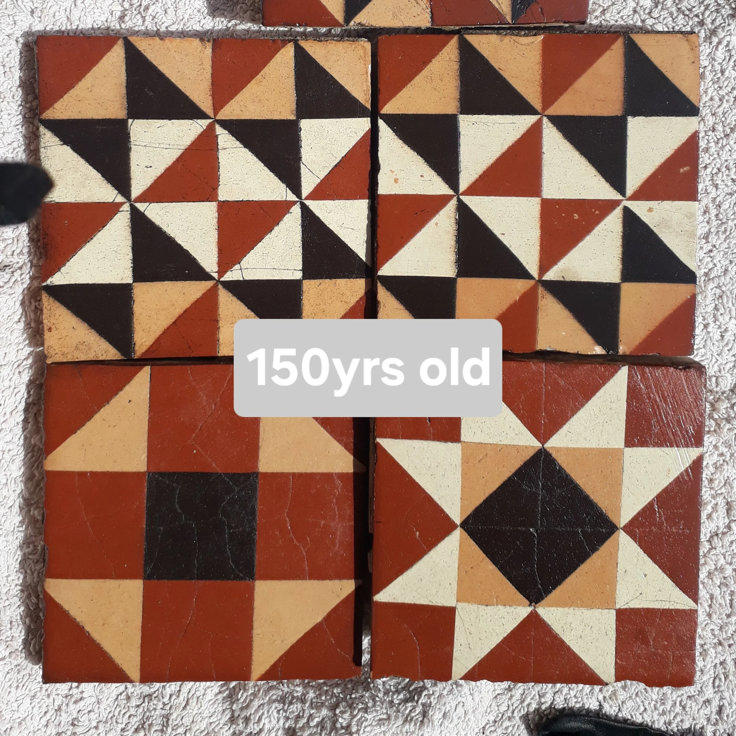 Four vintage tiles with geometric patterns in black, white, and red, arranged in a 2x2 grid, labeled as 150 years old