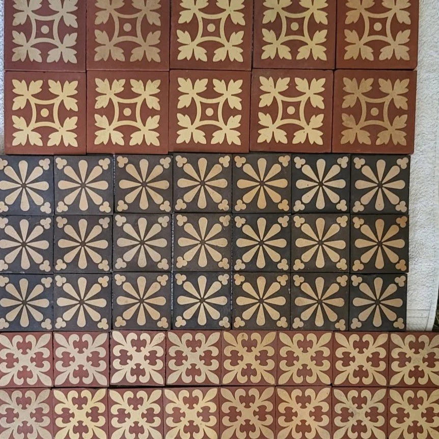 Decorative ceramic tiles with geometric floral patterns in red, black, and beige colors.