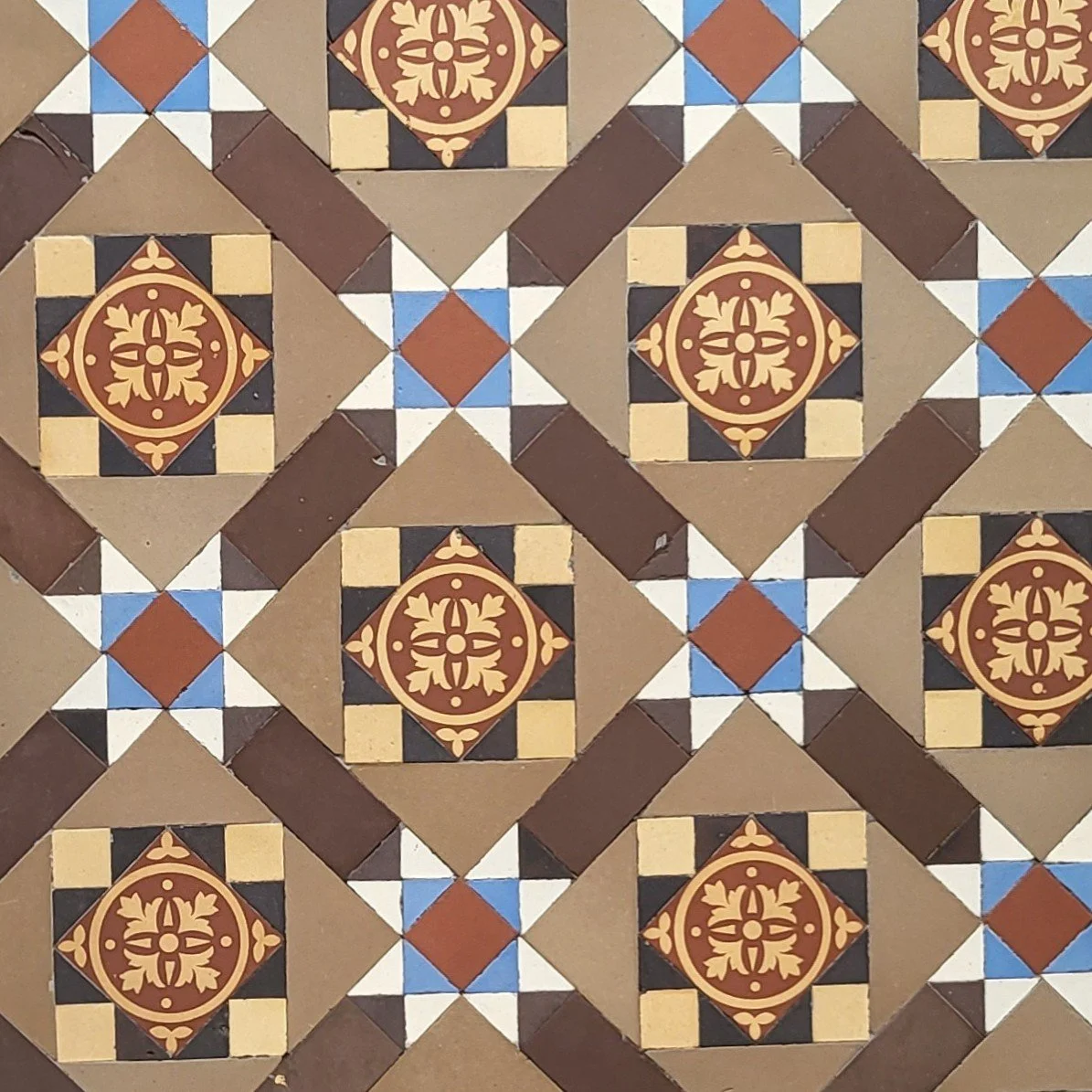 Patterned ceramic tiles with geometric and floral designs in brown, beige, black, white, and blue colors.