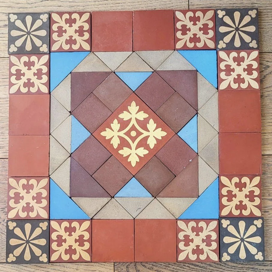 Decorative tile pattern with a central floral design, surrounded by color blocks and geometric patterns in red, blue, beige, and black.