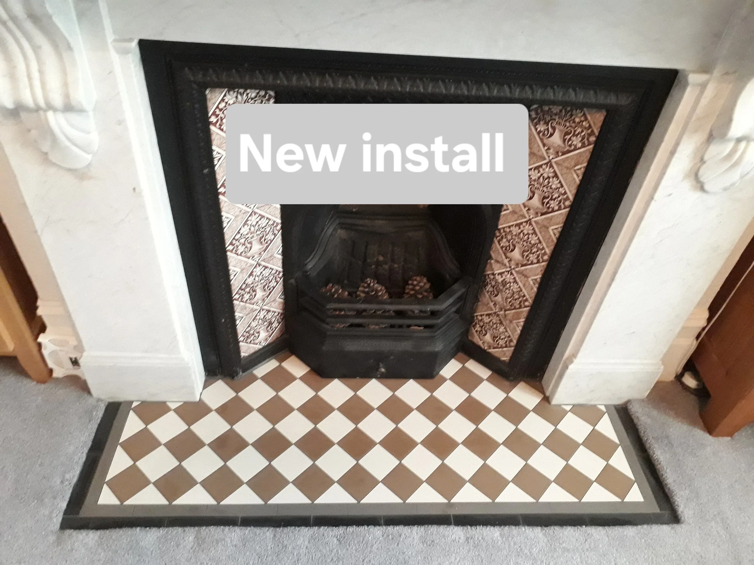 A fireplace with black frame and new tile hearth, featuring a sign that reads 'New install'.