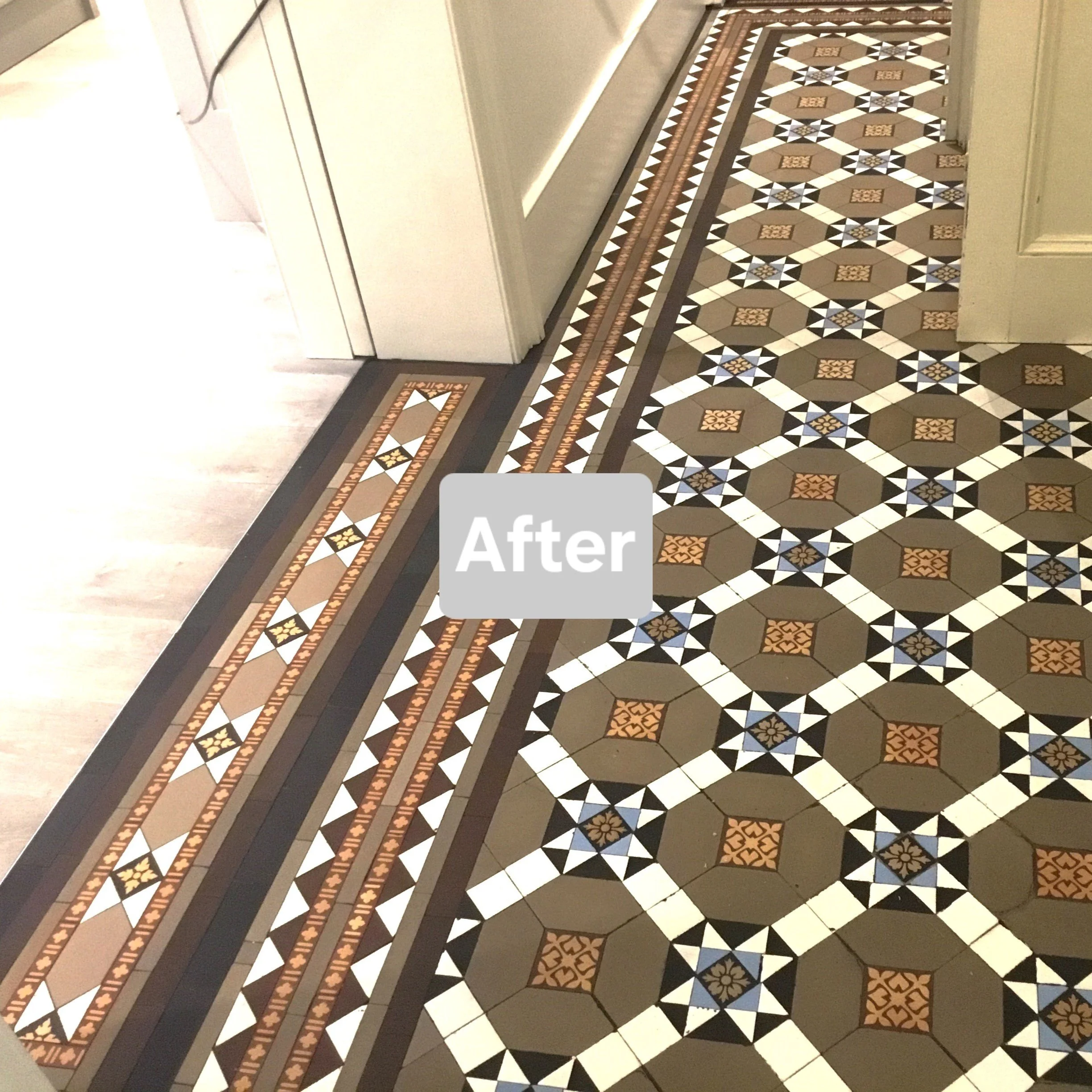 Patterned ceramic floor tiles with geometric and floral designs in brown, white, black, and blue colors in a kitchen.