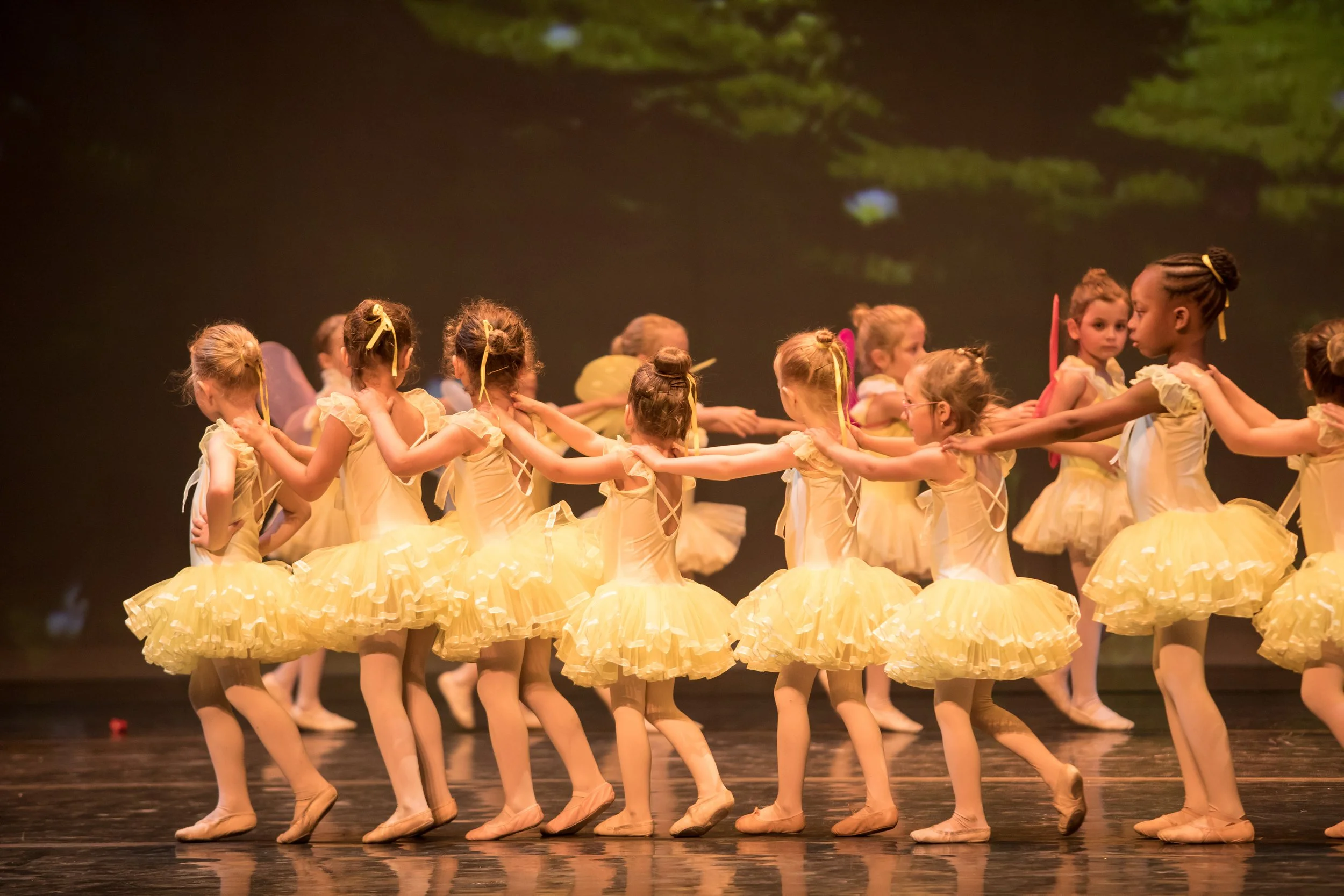 Groupe de jeunes danseuses en costumes jaunes lors d'une performance sur scène.