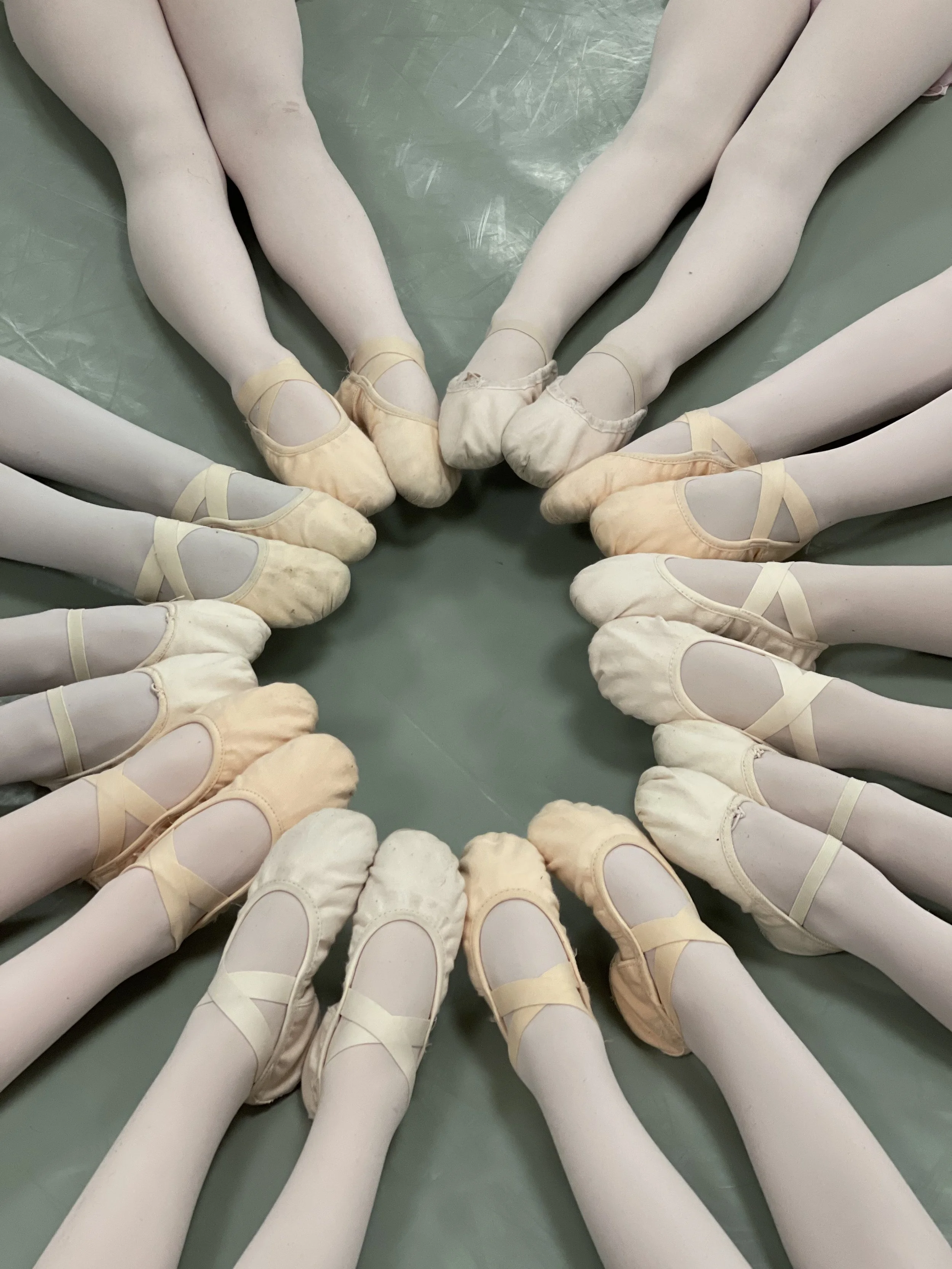 paires de chaussons de ballet blanc rangées en cercle sur le sol. association danse allegro.