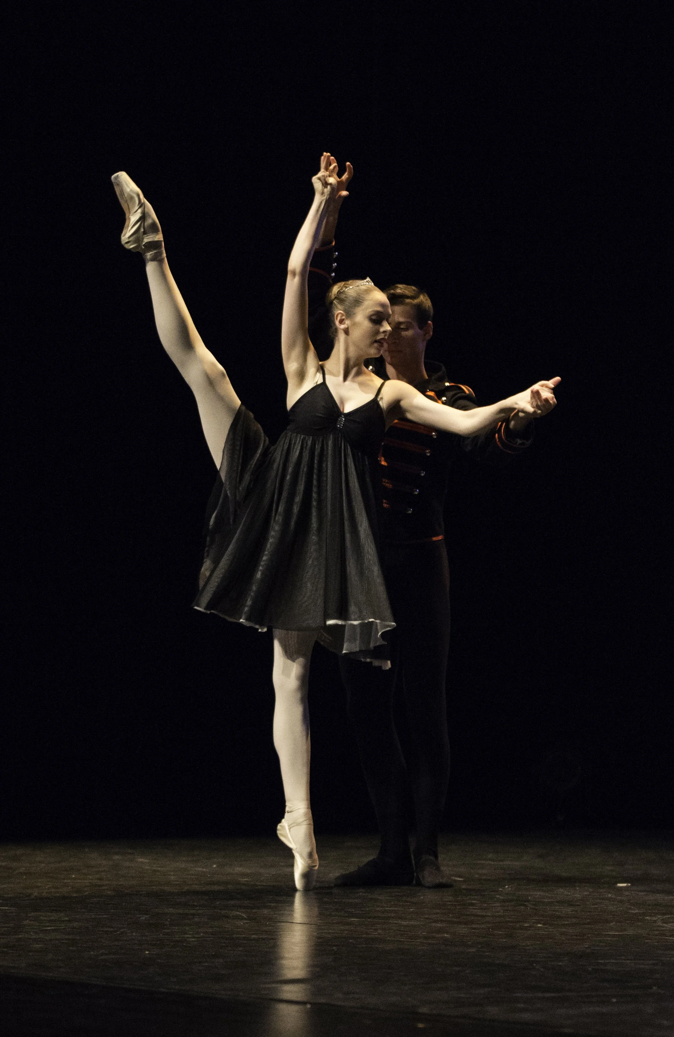 Deux danseurs classiques, l'un masculin et l'autre féminin, en plein ballet sur scène, avec la femme en position de pointe et le homme la soutenant, dans une scène de danse théâtrale.