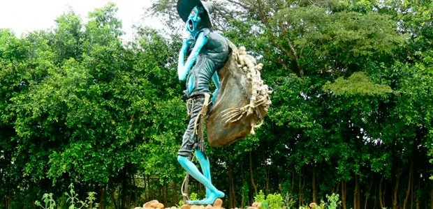 Photograph of an "El Silbón" statue. He has blue skin and a sack full of human bones