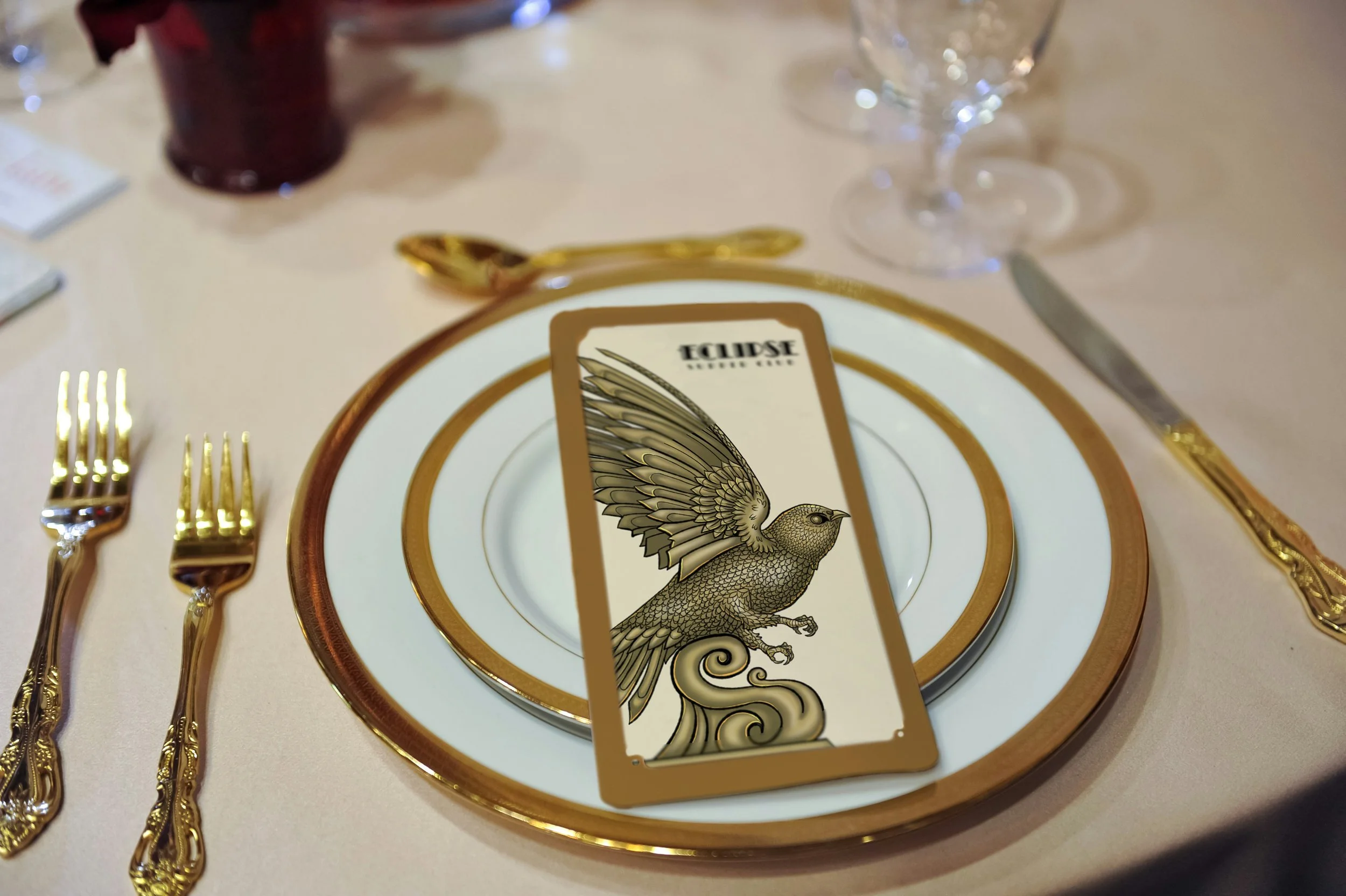 Small restaurant menu mockup on a plate with golden linings. It depicts a Black switf statue and the Eclipse Supper Club logo.